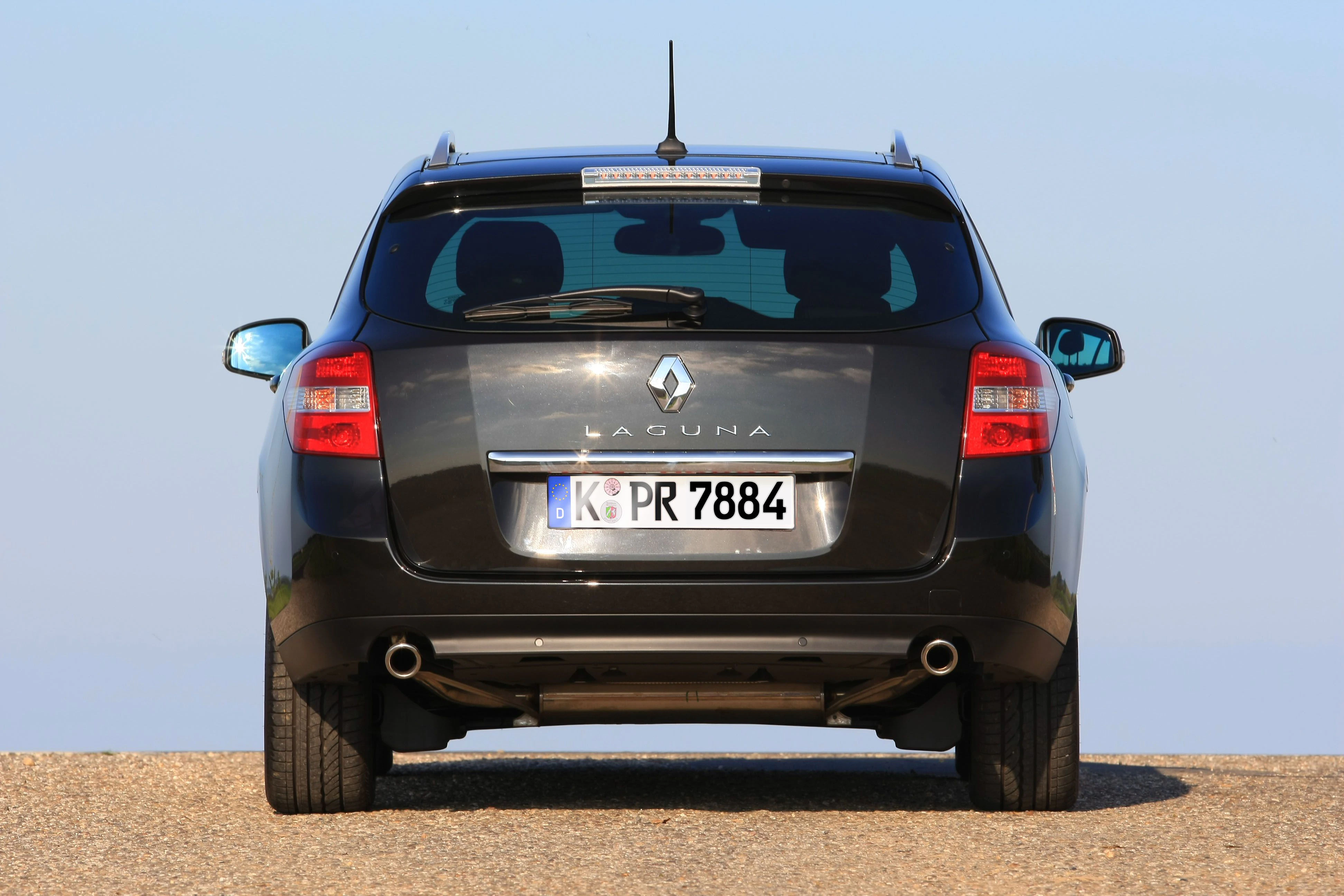 Schwarzer Renault Laguna Kombi, Heckansicht, auf einer Straße bei blauem Himmel. Nummernschild: K PR 7884.