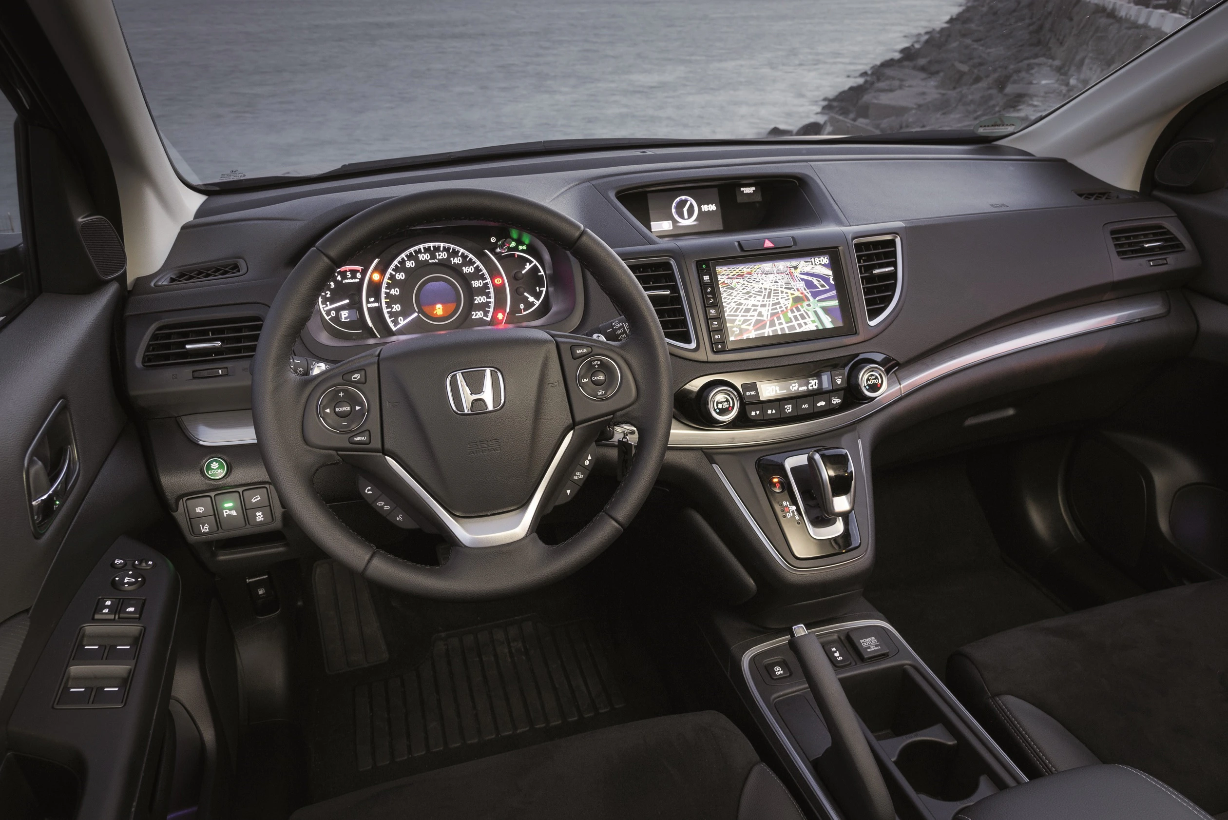 Innenraum eines Honda-Autos mit Lenkrad, Tachometer und Navigationssystem. Moderne Armaturen mit Holzdekor und Bedienelementen.