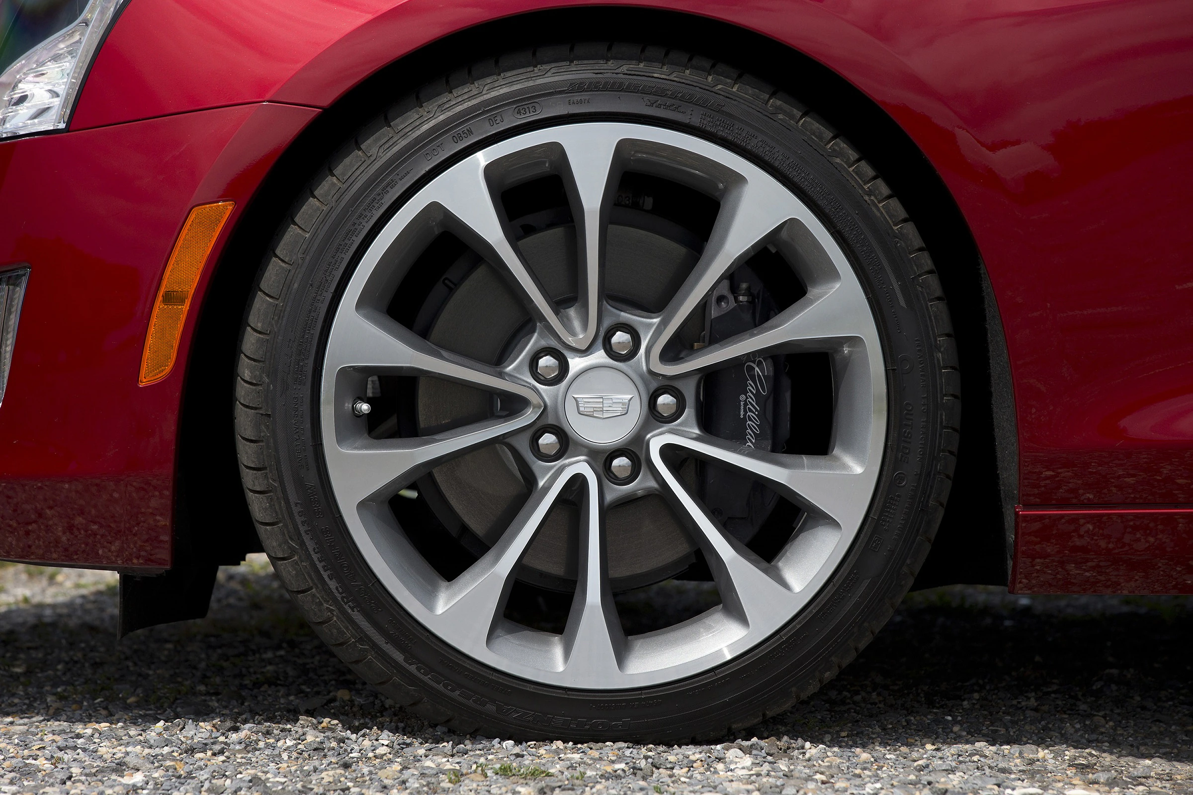 Rotes Auto mit silbernem Felgen-Design, das auf einem Kiesboden steht.