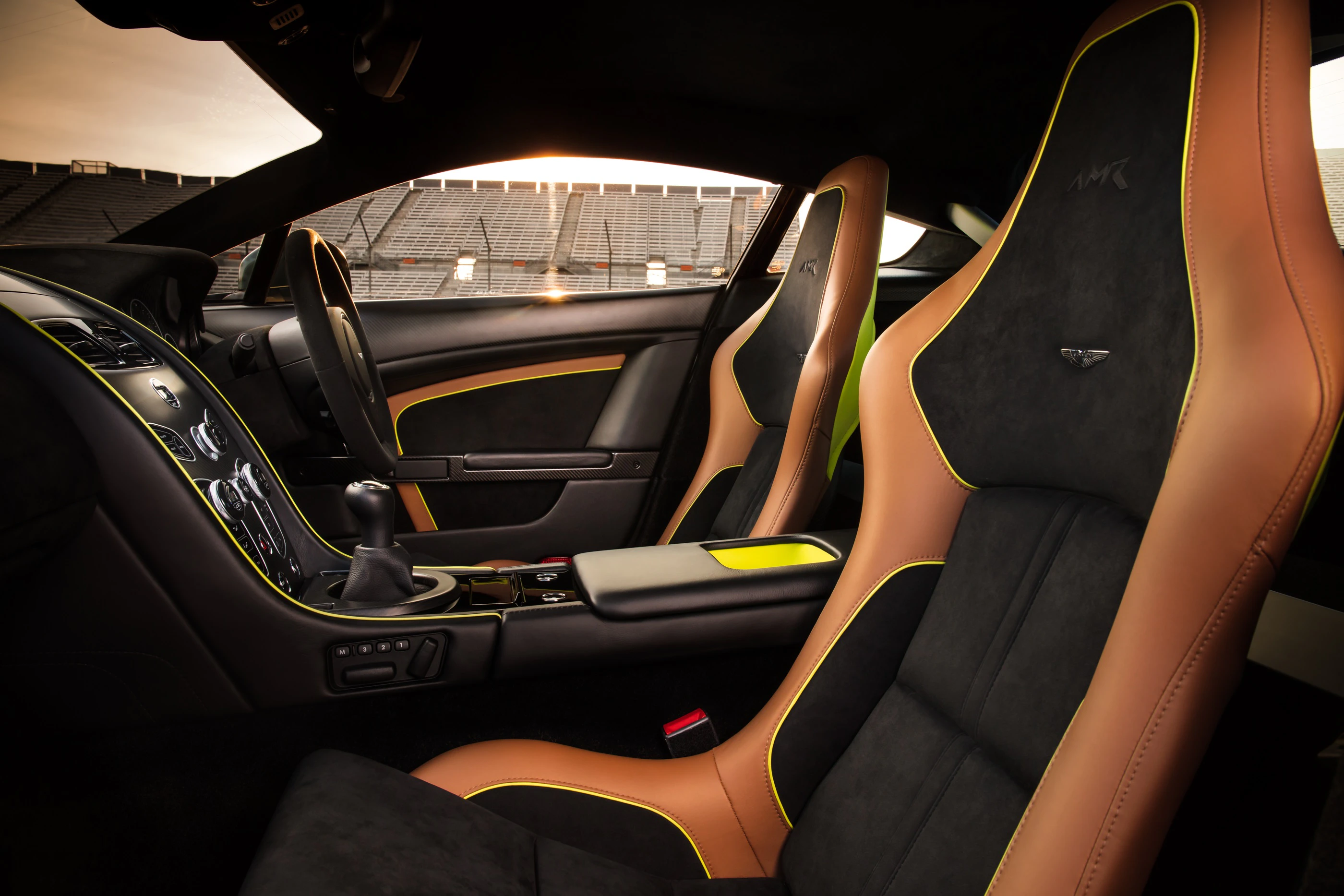Innenraum eines Luxusautos mit braun-schwarzen Ledersitzen, modernem Armaturenbrett und Sonnenlicht, das durch die Fenster scheint.