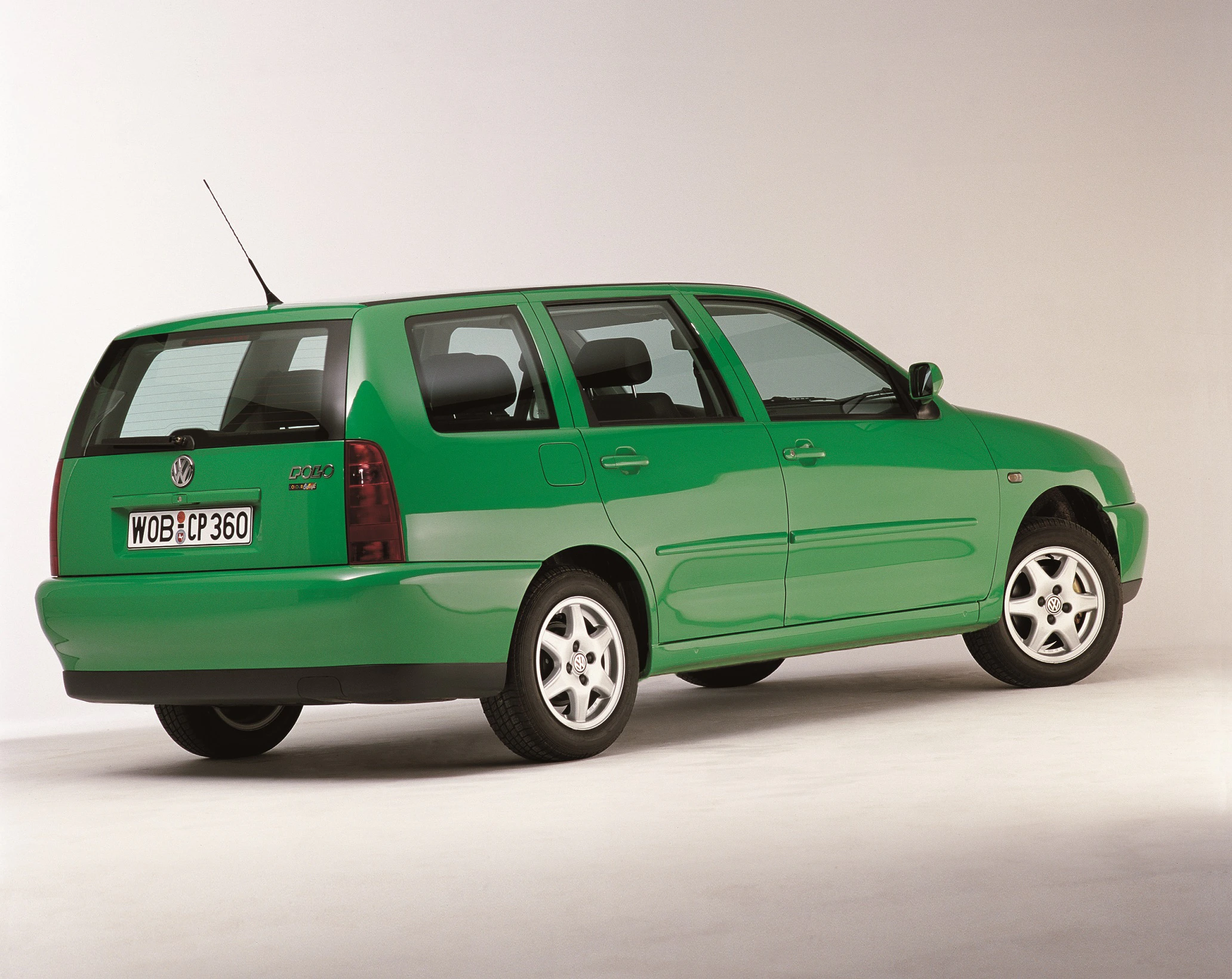 Grüner VW Polo Variant Kombi aus den 1990er Jahren, Seitenansicht von hinten auf hellem Hintergrund.