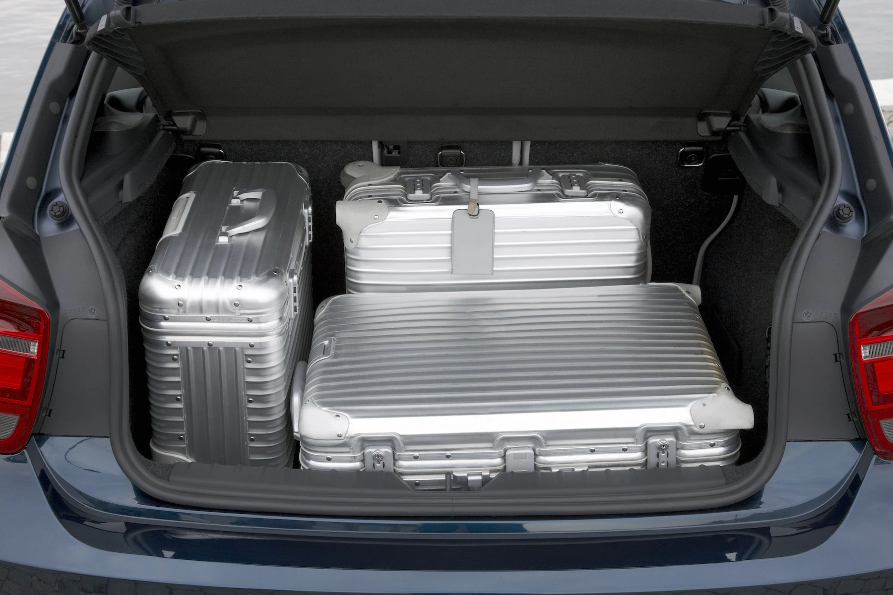 Offener Kofferraum eines Autos mit drei silbernen Aluminiumkoffern, ordentlich gestapelt und bereit für die Reise.
