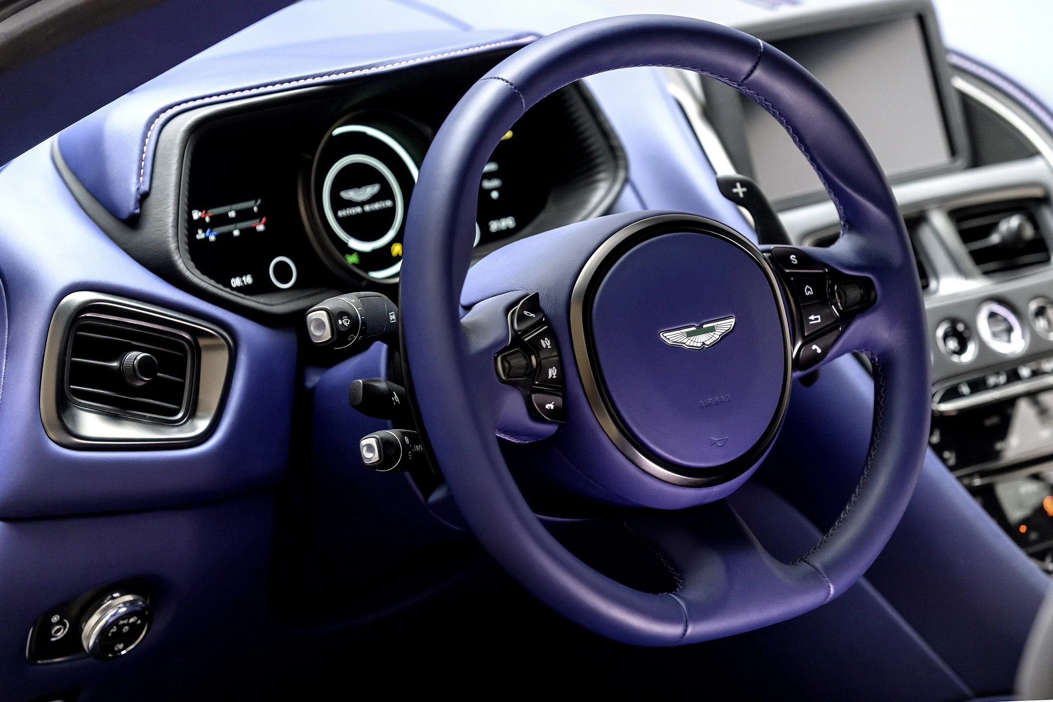 Lenkrad eines luxuriösen Autos mit blauem Leder, digitalem Display und modernen Bedienelementen.