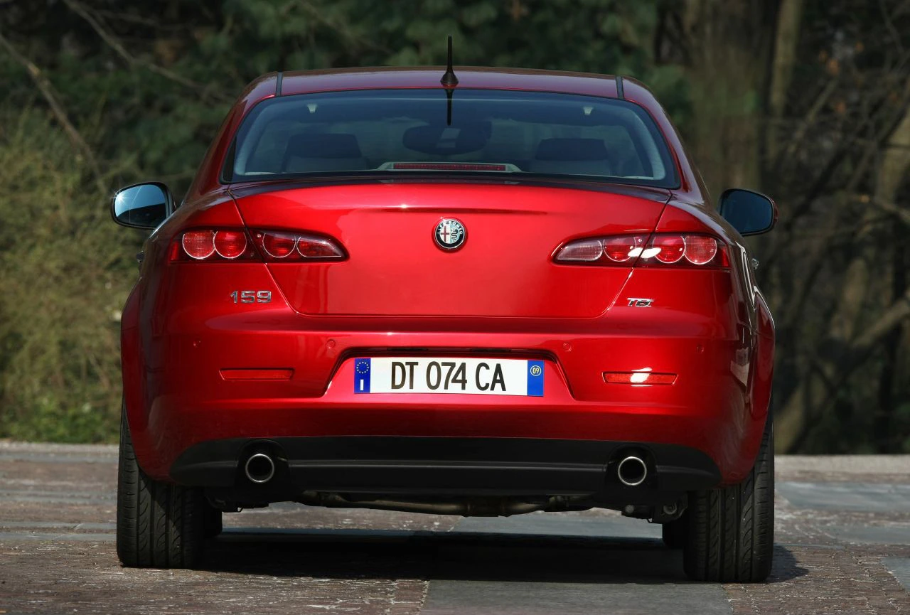 Rotes Auto, Rückansicht, mit italienischem Kennzeichen, geparkt auf einer Straße. Alfa Romeo 159 mit markanten Rücklichtern und Auspuff.