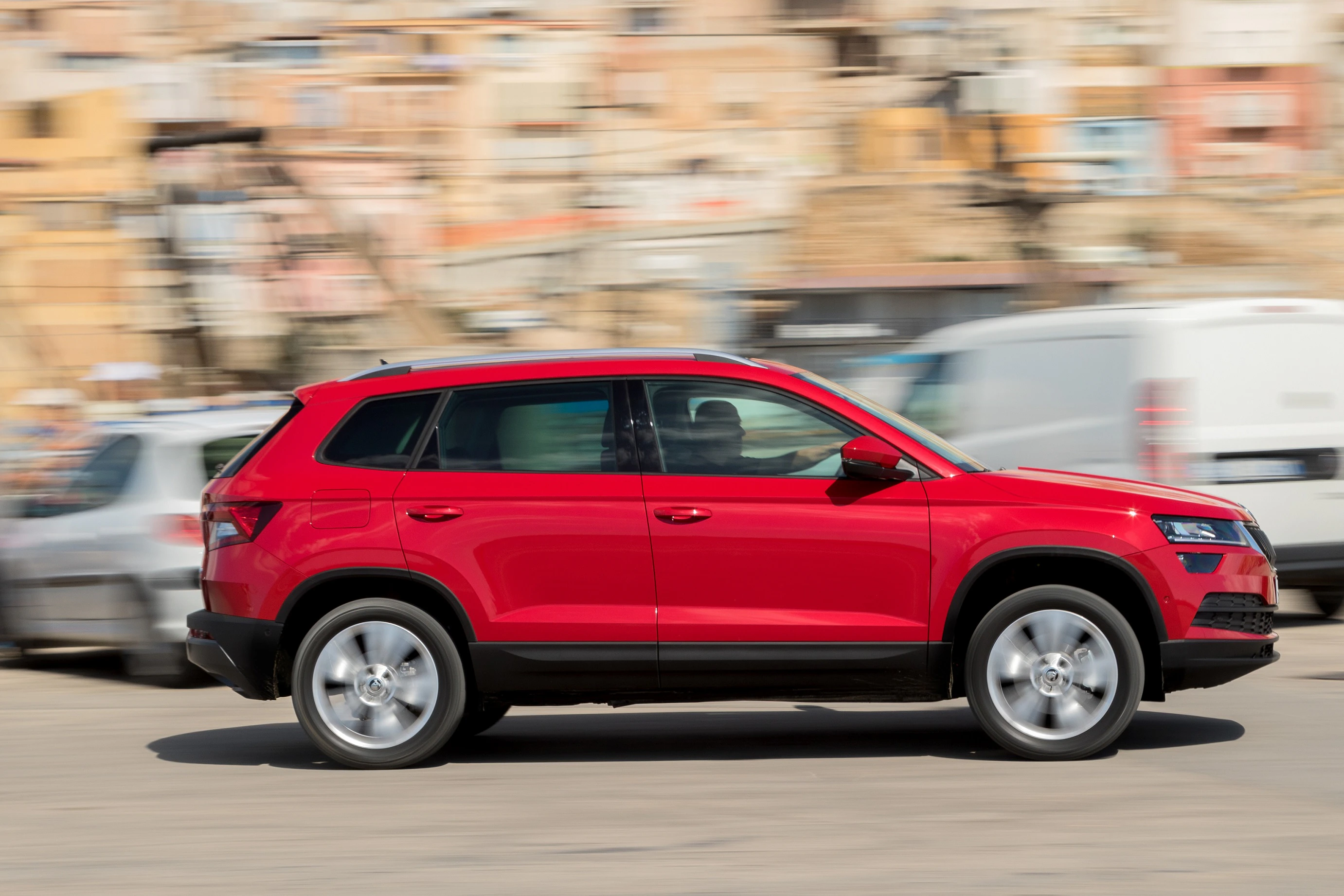 Roter SUV fährt schnell auf einer Straße, Hintergrund unscharf.