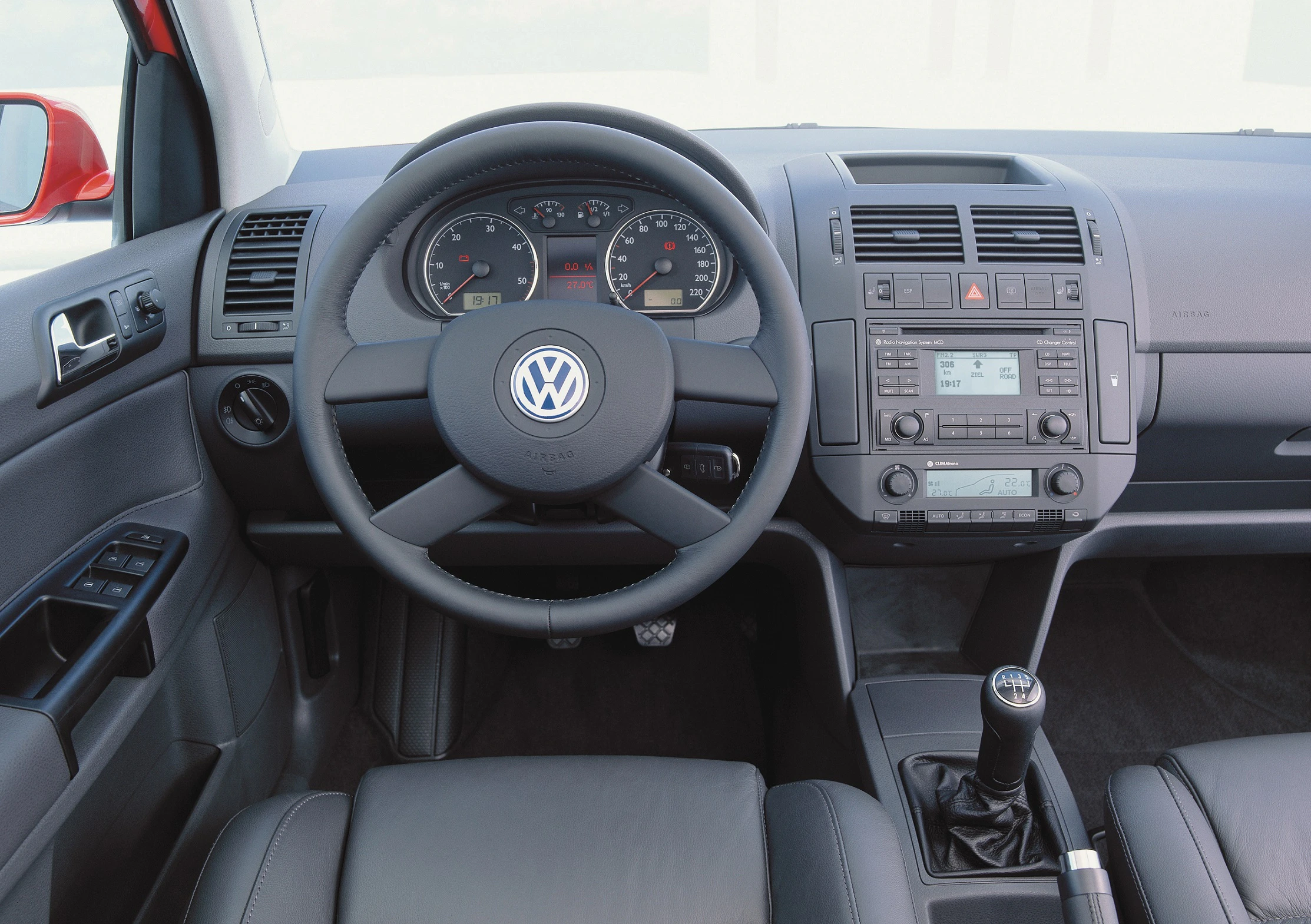 Lenkrad und Armaturenbrett eines Volkswagen mit Tachometer, Klimaanlage und Schaltknüppel in grauem Innenraum.
