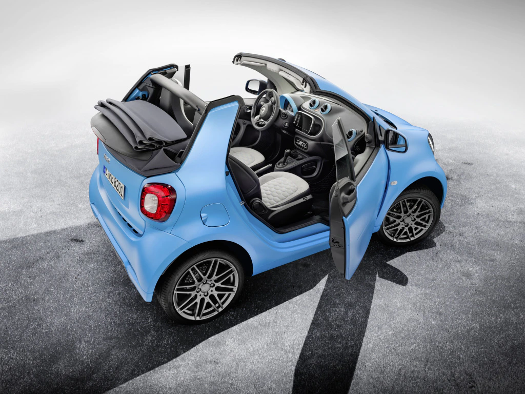 Blauer Smart Cabrio mit geöffnetem Verdeck und Türen, moderne Innenausstattung, auf grauem Untergrund.