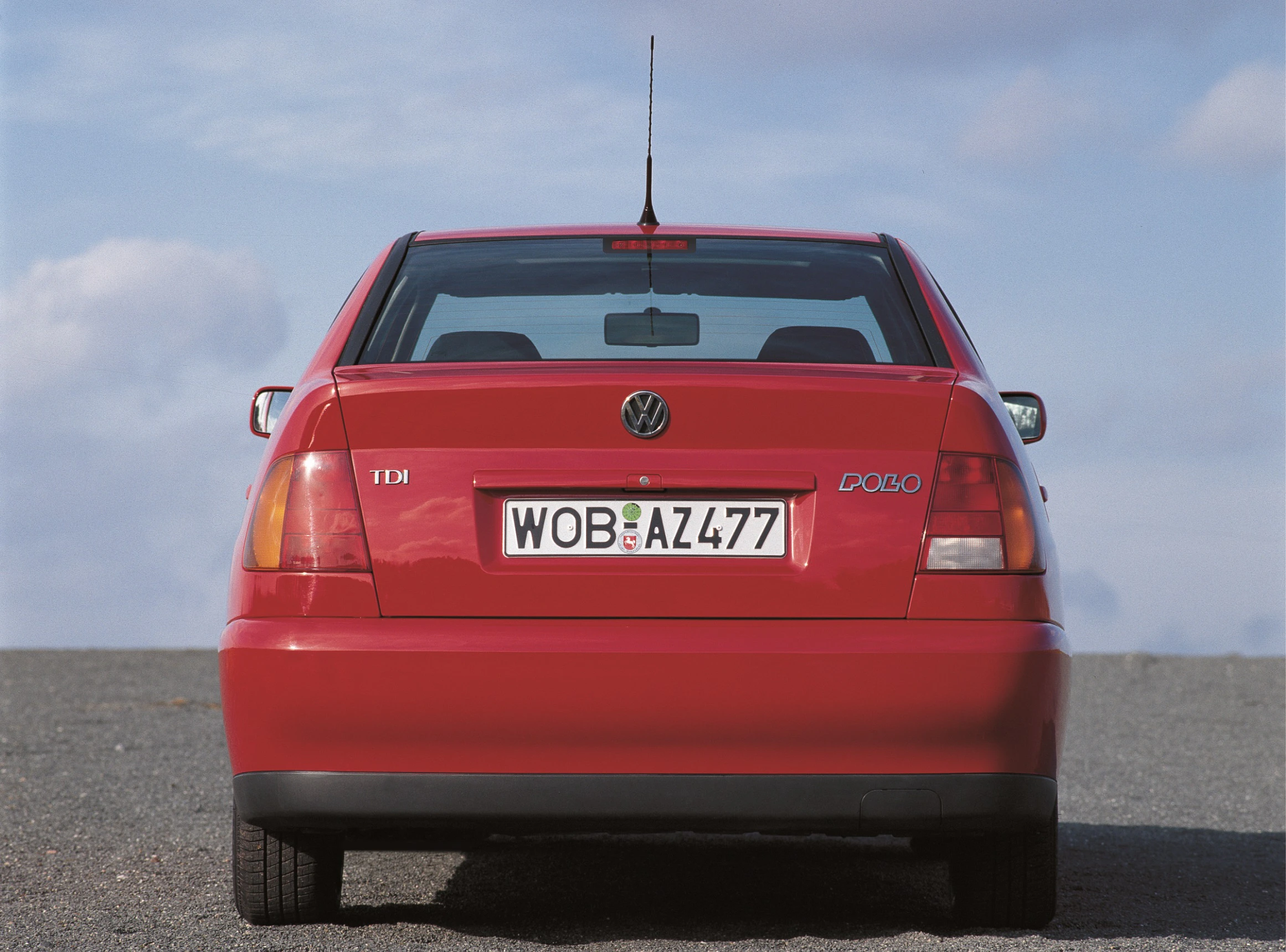 Rotes Auto, VW Polo TDI, Ansicht von hinten mit Kennzeichen WOB-AZ477, Himmel im Hintergrund.