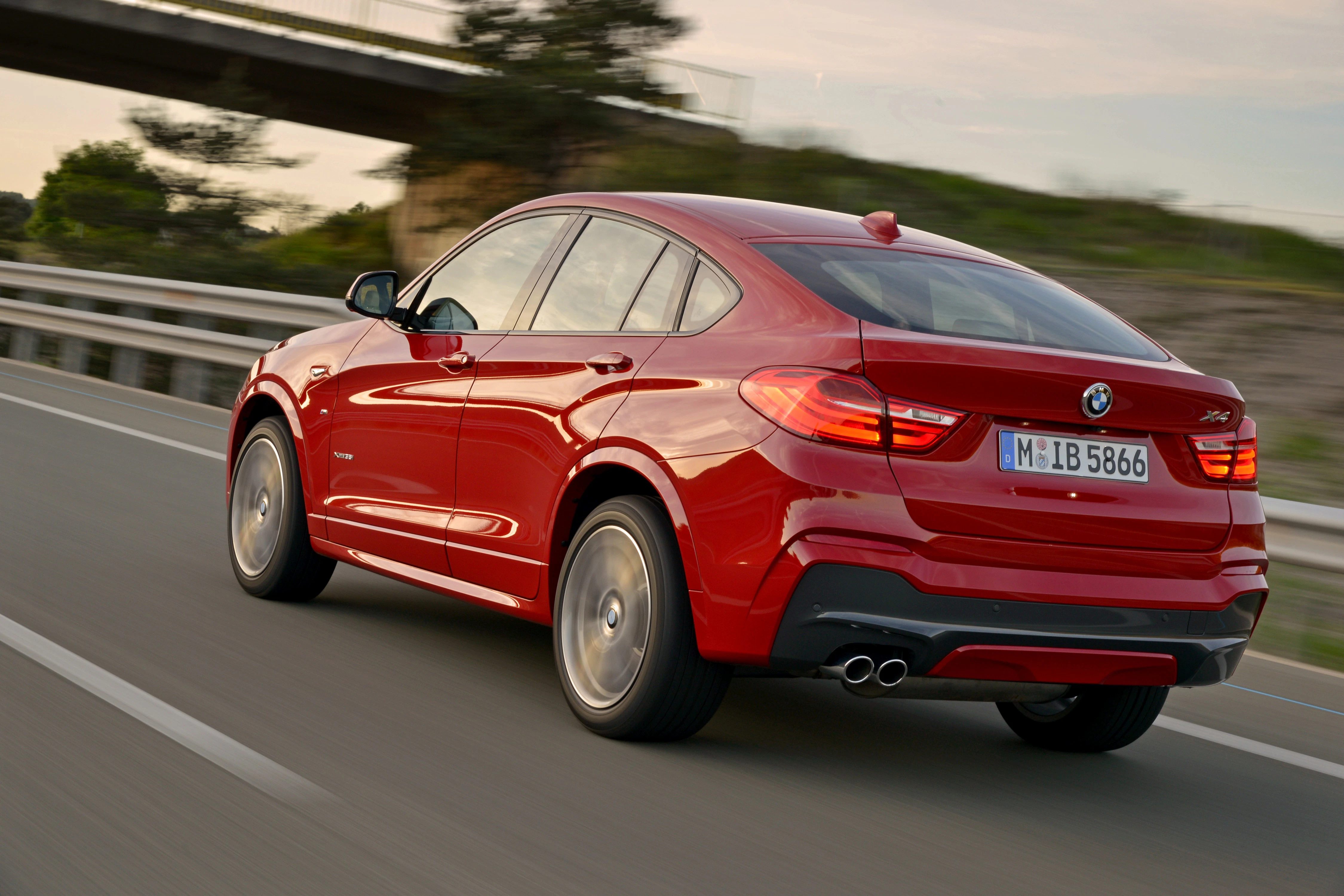 Roter BMW SUV fährt auf einer Straße bei Sonnenuntergang, zeigt dynamisches Design und moderne Linienführung.