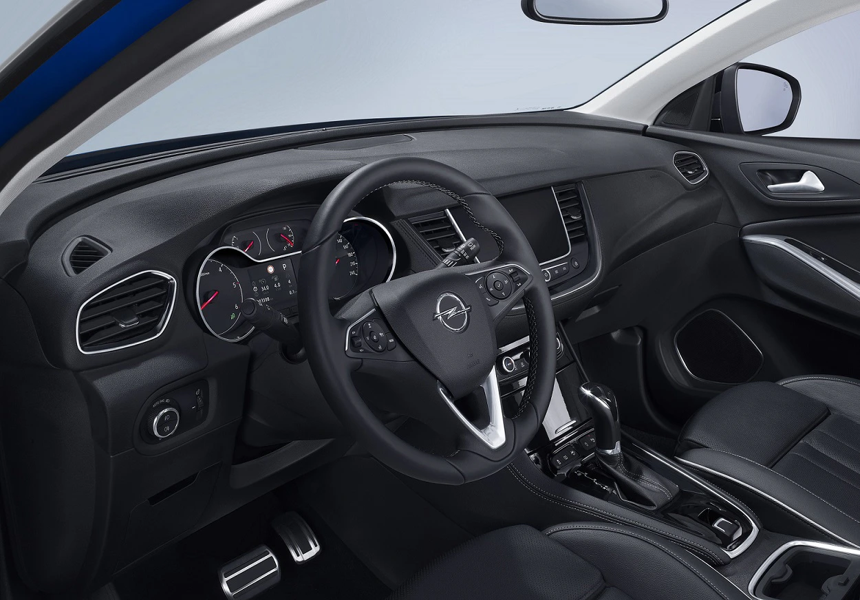 Innenraum eines modernen Autos mit Lederlenkrad, digitalem Tacho und Mittelkonsole. Das Interieur ist in dunklen Tönen gehalten.