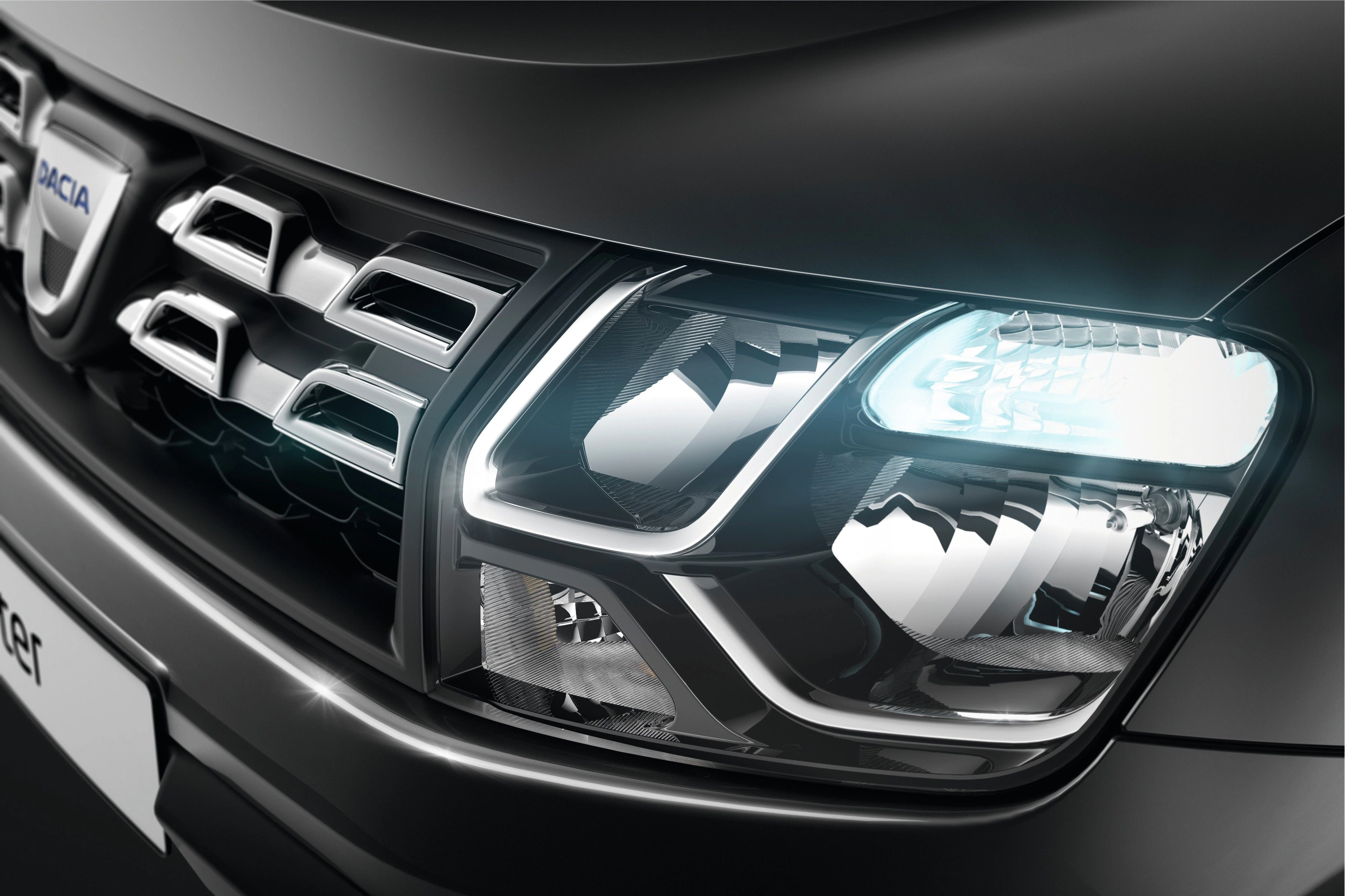 Nahaufnahme eines schwarzen Autoscheinwerfers und Kühlergrills, die scharfe Konturen und ein modernes Design aufweisen.