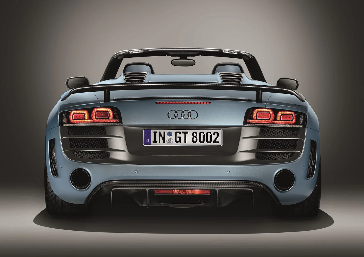 Ein blauer Audi R8 Cabrio, Rückansicht, mit geöffnetem Verdeck. Sichtbare Auspuffrohre und Rücklichter.