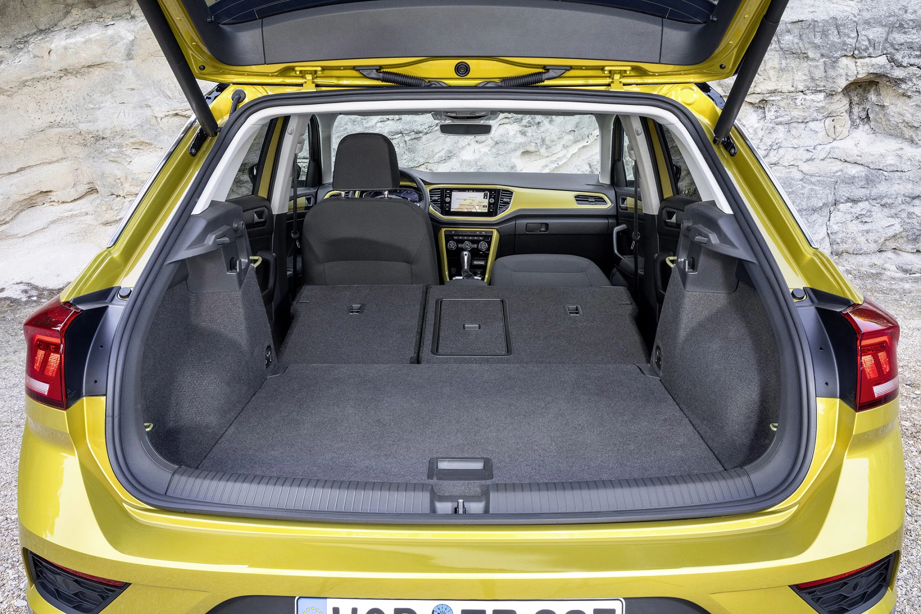 Kofferraum eines gelben Autos mit umgeklappten Rücksitzen, die großzügigen Laderaum bieten. Ansichten von hinten nach vorne, Klappe geöffnet.