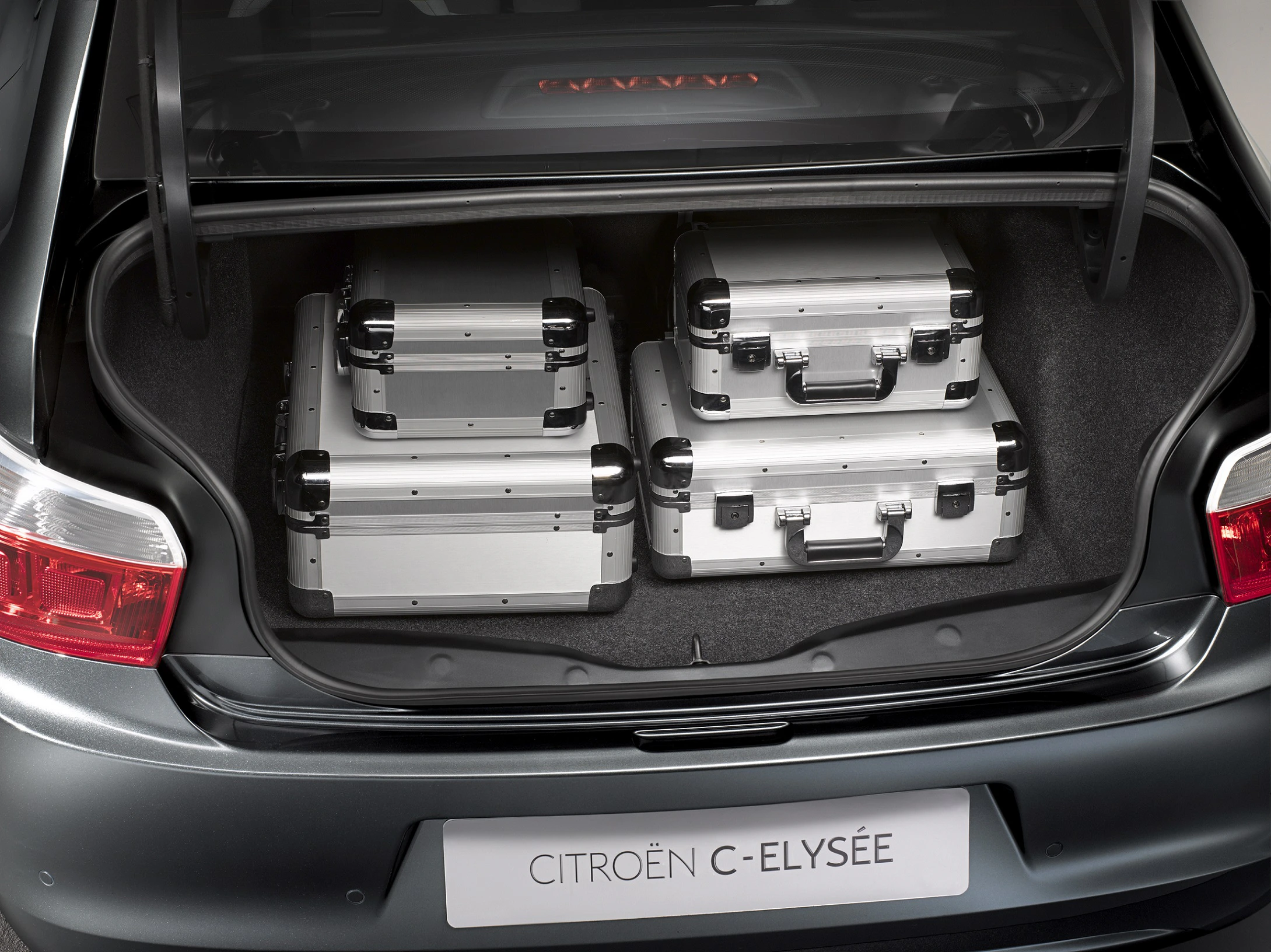 Ein Auto-Kofferraum, der drei silberne Metallkoffer enthält. Das Auto ist ein Citroën C-Elysée.