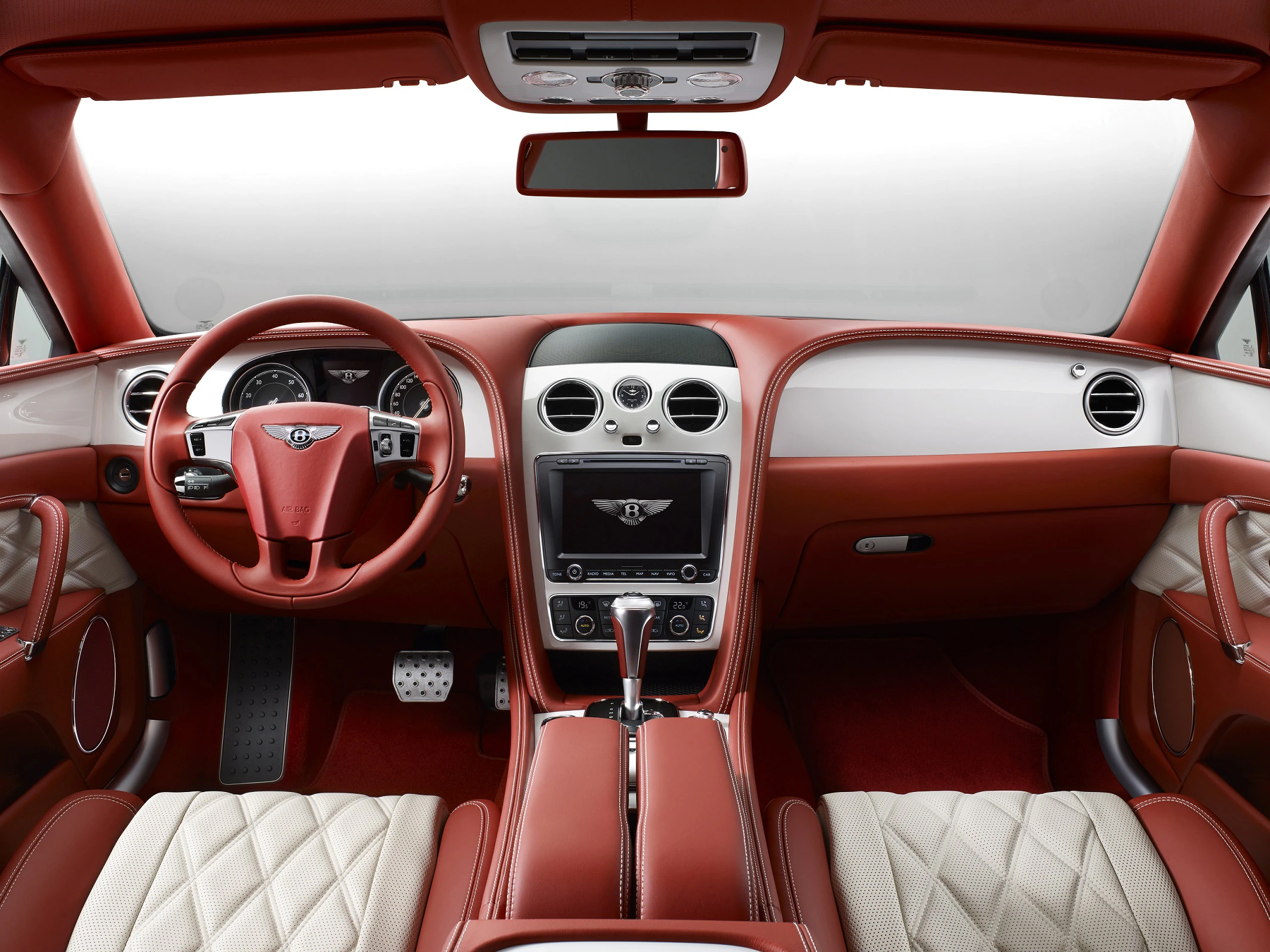 Luxuriöser Auto-Innenraum mit roten Lederpolstern, modernen Armaturen und einem eleganten Lenkrad in zentraler Position.