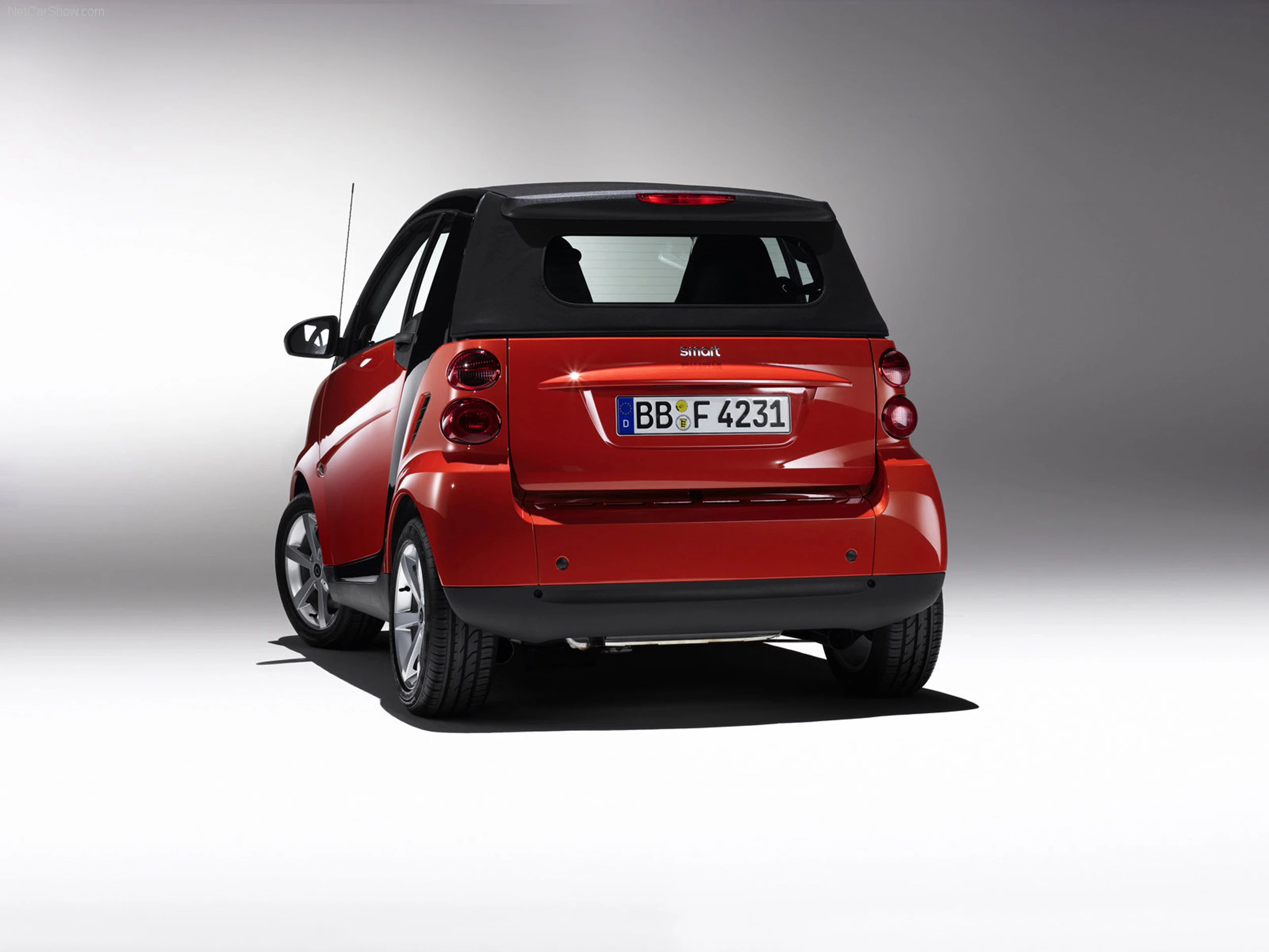 Roter Smart mit schwarzem Dach, Heckansicht. Das Auto steht auf einem neutralen Hintergrund. Nummernschild: BB * F 4231.