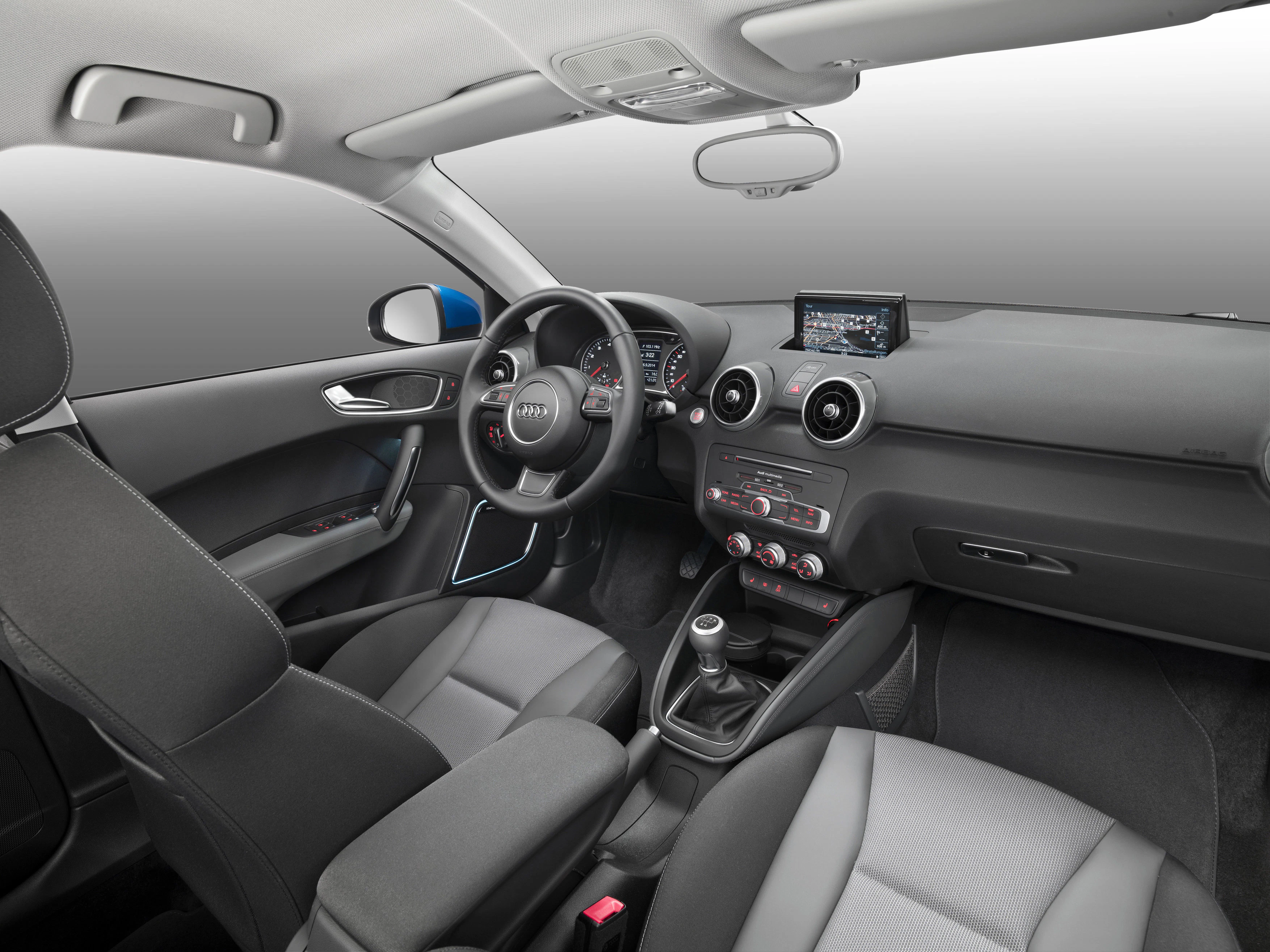Innenraum eines modernen Fahrzeugs mit grauen Sitzen, Touchscreen, Lenkrad und Schalthebel. Schlichtes Design mit schwarzem und grauem Interieur.