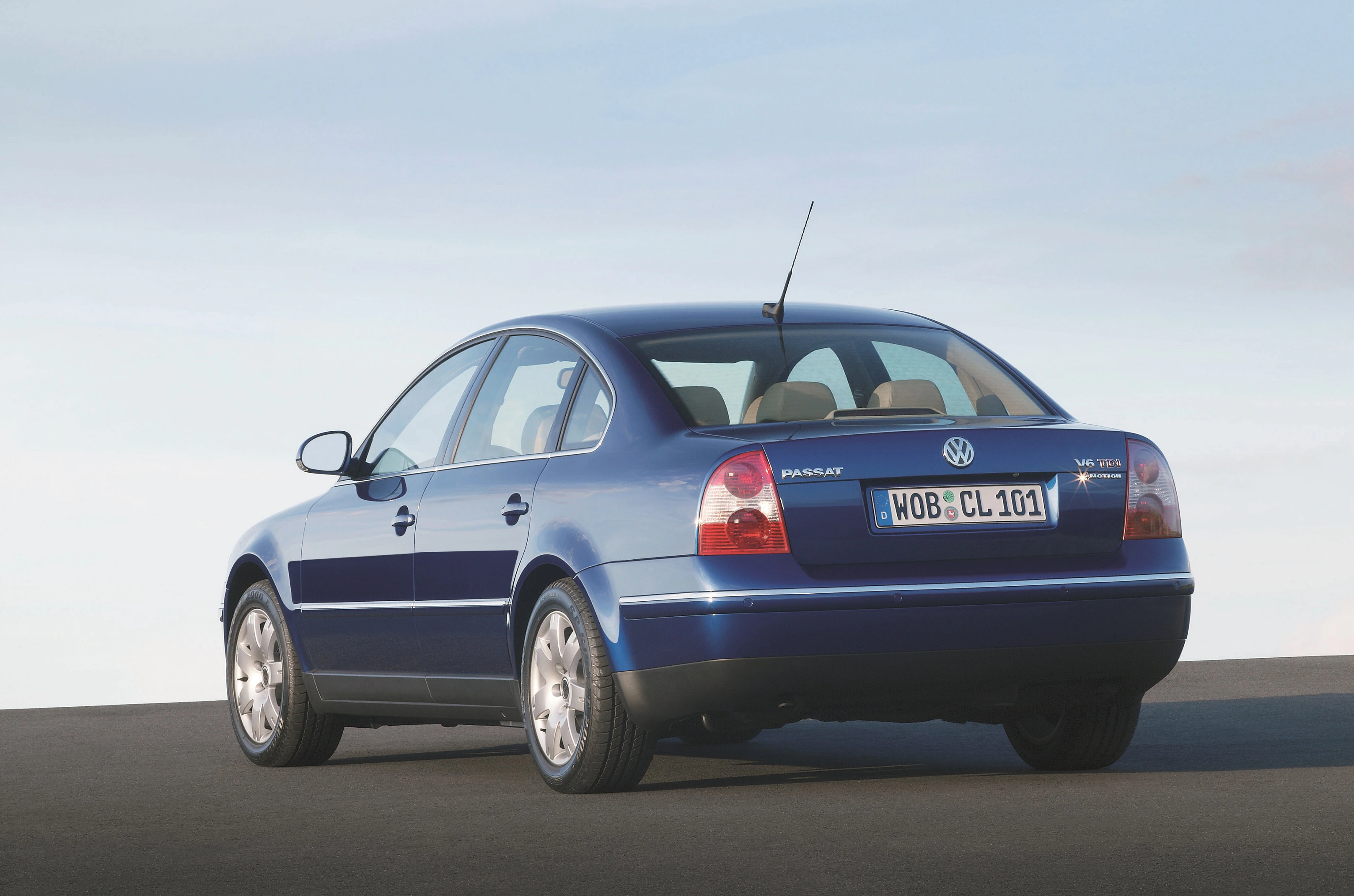 Blauer Volkswagen Passat Limousine, seitliche Rückansicht, auf offener Straße bei Tageslicht geparkt.
