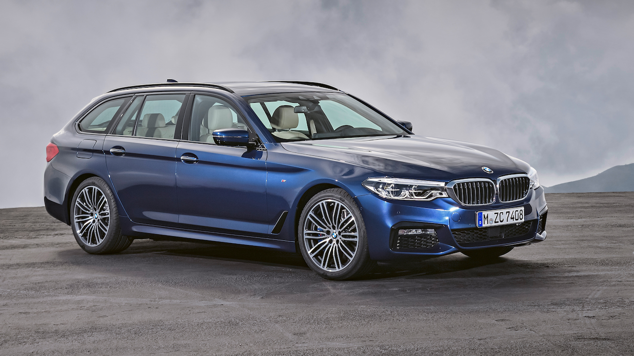 Blauer Kombi auf dunkler Straße vor wolkigem Himmel. Moderne Limousine, markantes Design, silberne Felgen.