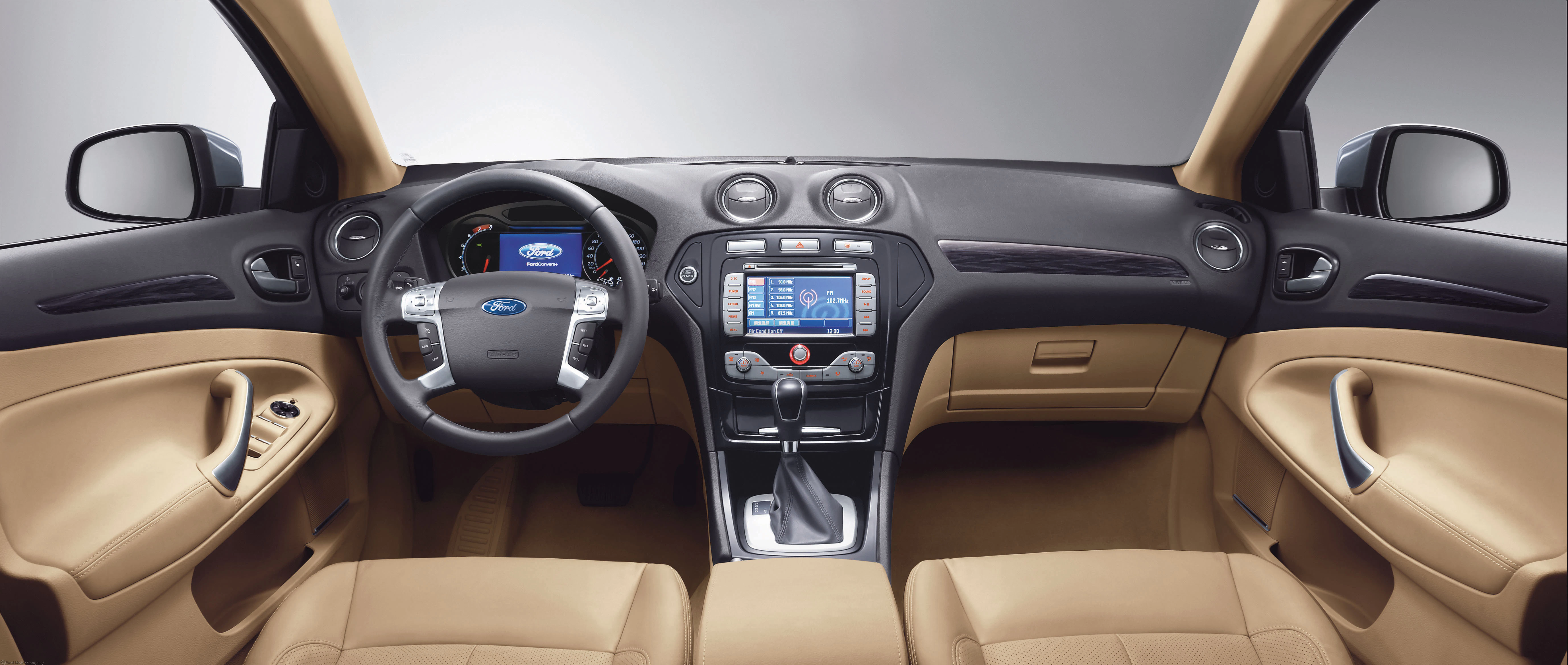 Innenraum eines Autos mit beigem Leder, Lenkrad mit Ford-Logo, Touchscreen in der Mitte und Armaturenbrett mit Bedienelementen.