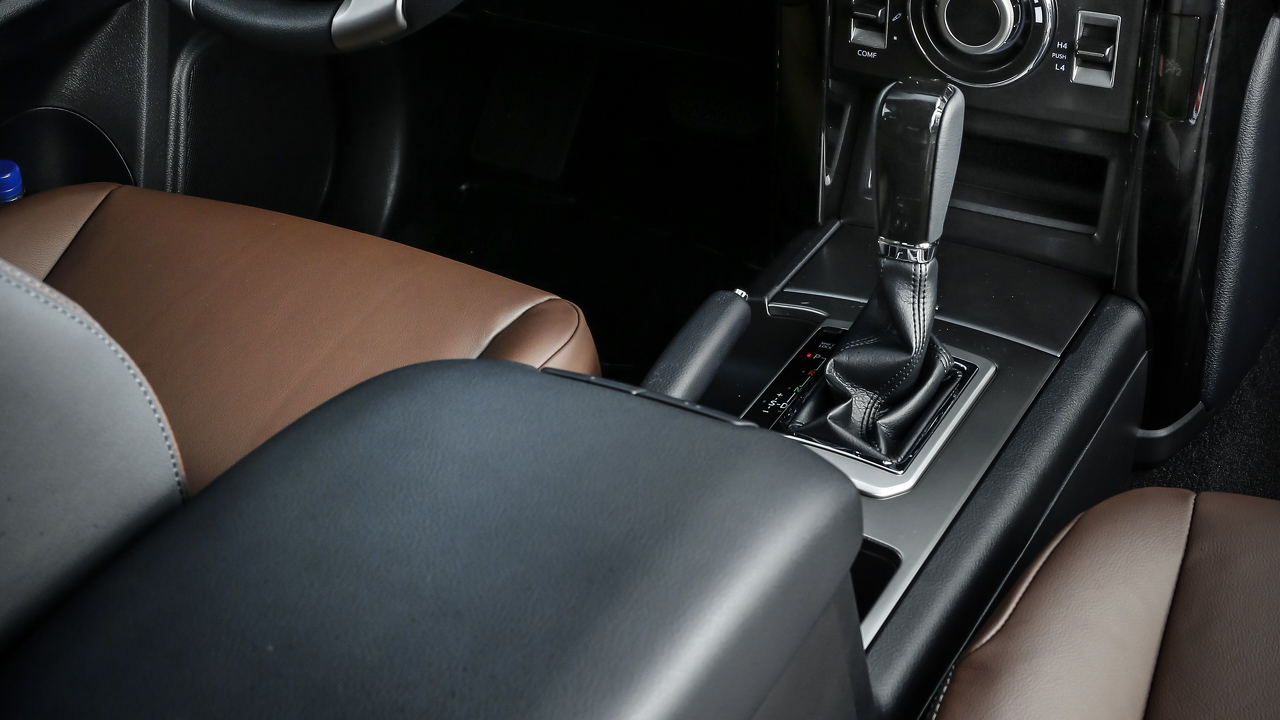 Nahaufnahme eines Autoinnenraums mit Automatikgetriebe, Ledersitzen in Braun und Mittelkonsole.