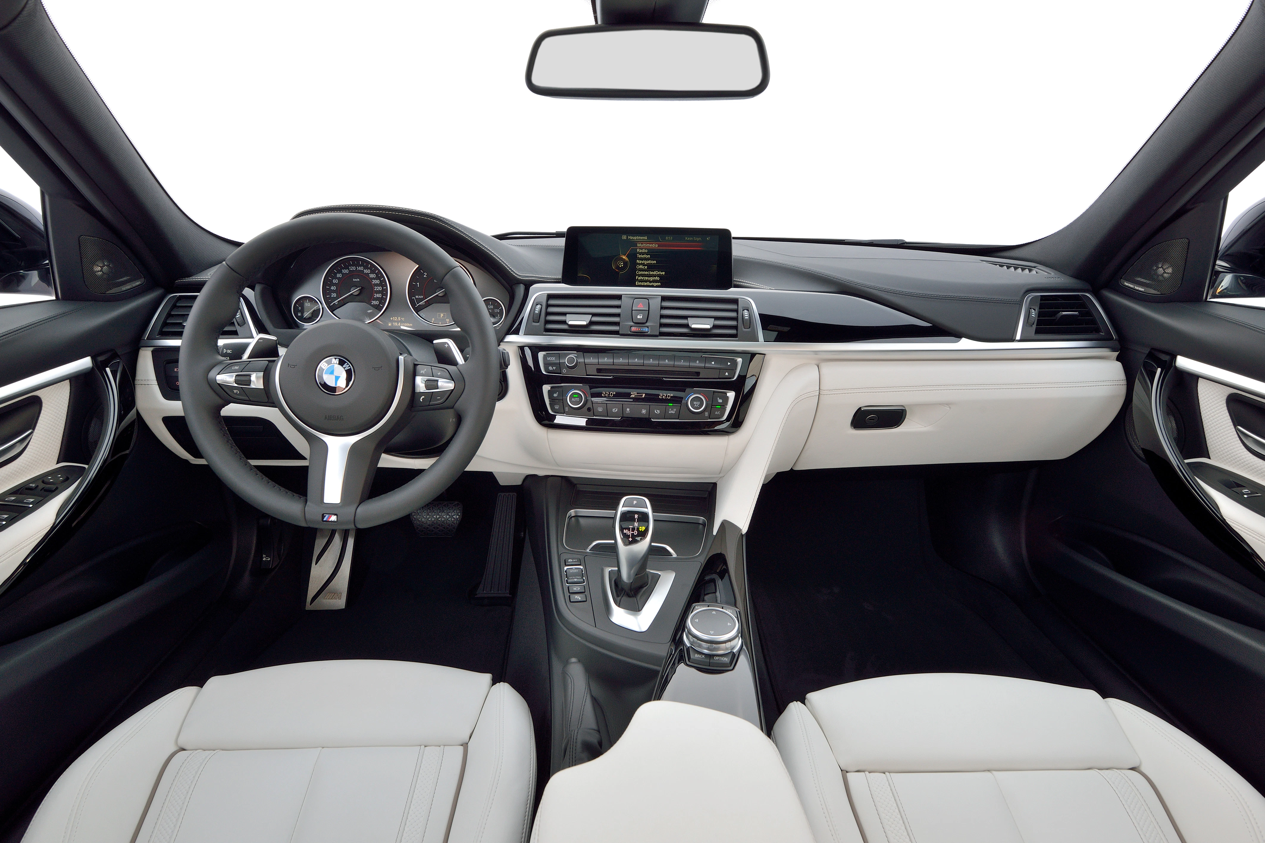 Innenraum eines BMWs mit Lederpolstern, Lenkrad, Mittelkonsole und einem Bildschirm auf dem Armaturenbrett.