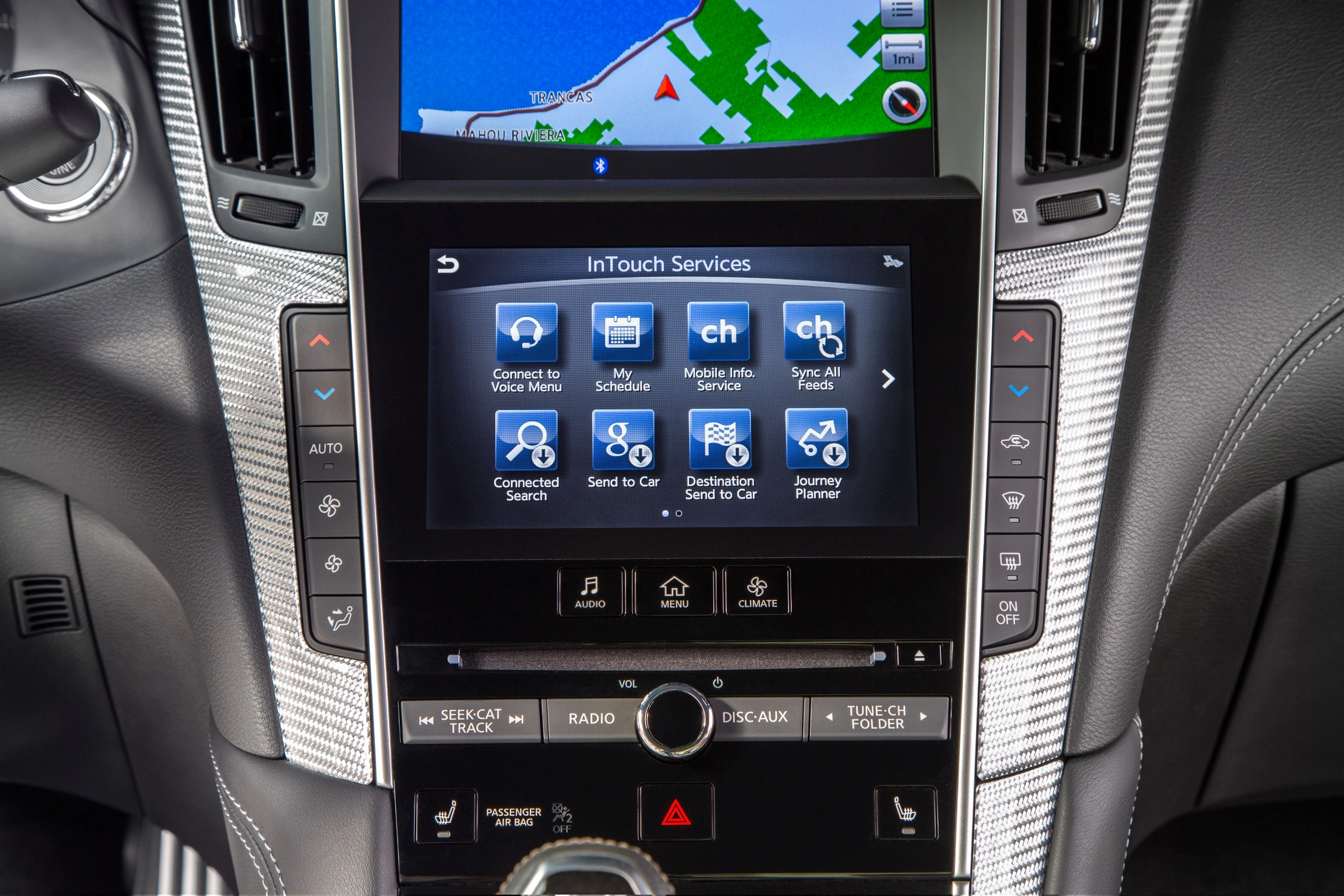 Nahaufnahme eines modernen Autonavigations- und Infotainmentsystems mit Touchscreen-Display, verschiedenen Apps und silbernen Seitenelementen.
