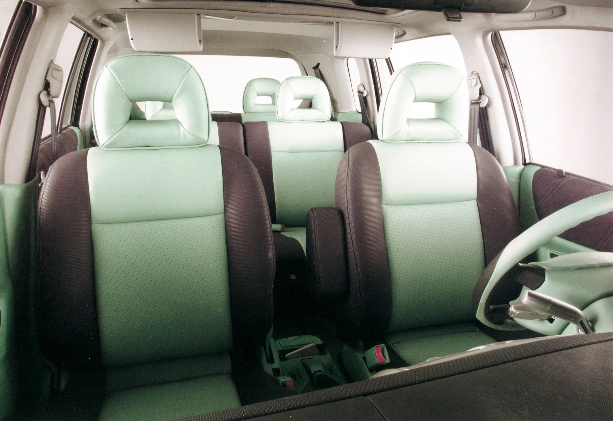 Innenraum eines Autos mit mintgrünen und schwarzen Sitzen, Lenkrad und Armaturenbrett. Modernes Design mit hellem Lichteinfall.