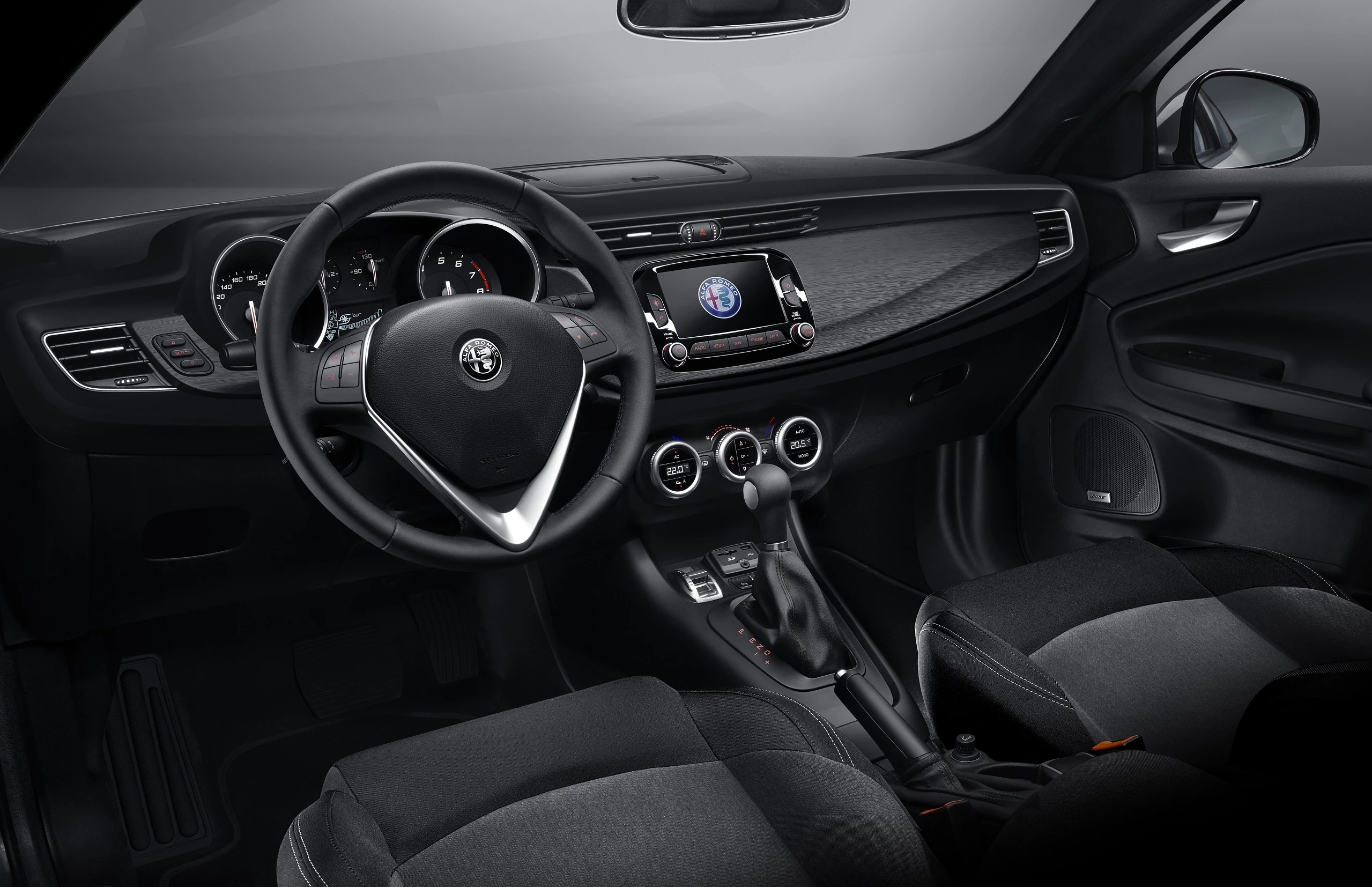 Innenraum eines Autos mit Lenkrad, Tachometer und Infotainmentsystem mit Alfa Romeo-Logo auf dem Bildschirm. Moderne, schwarze Ausstattung.