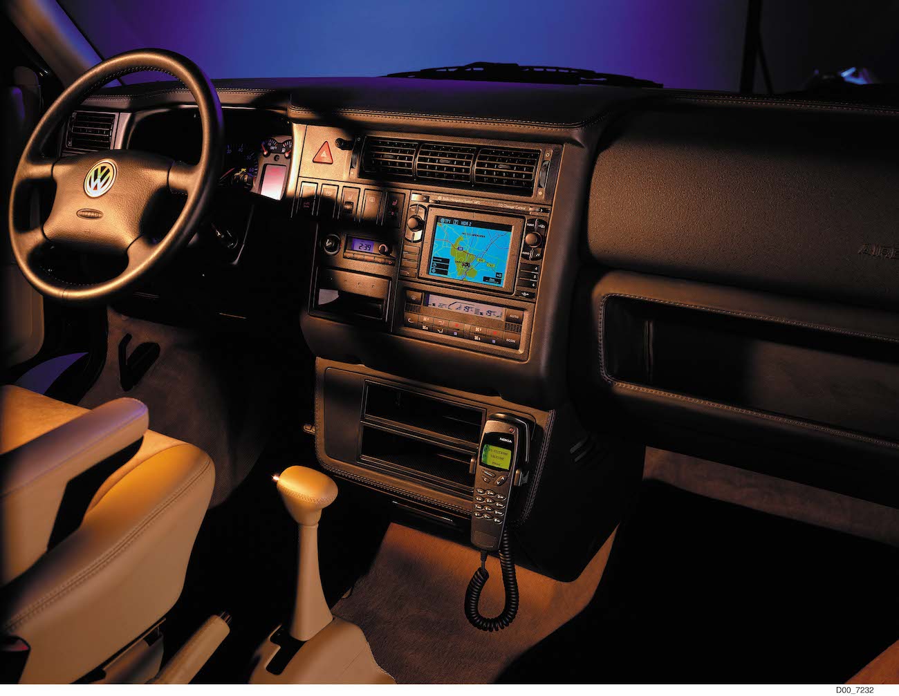 Innenraum eines Volkswagen mit Lederpolsterung, Navigationssystem, Telefon und Schaltknüppel. Beleuchtung in Blau- und Violetttönen.