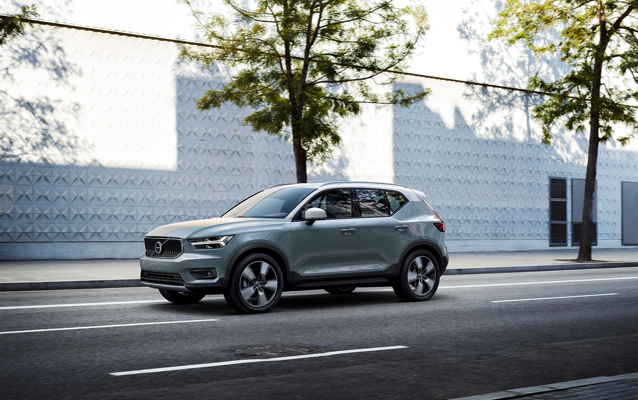 Silberner SUV parkt auf einer städtischen Straße, im Hintergrund moderne Architektur und Bäume bei Tageslicht.