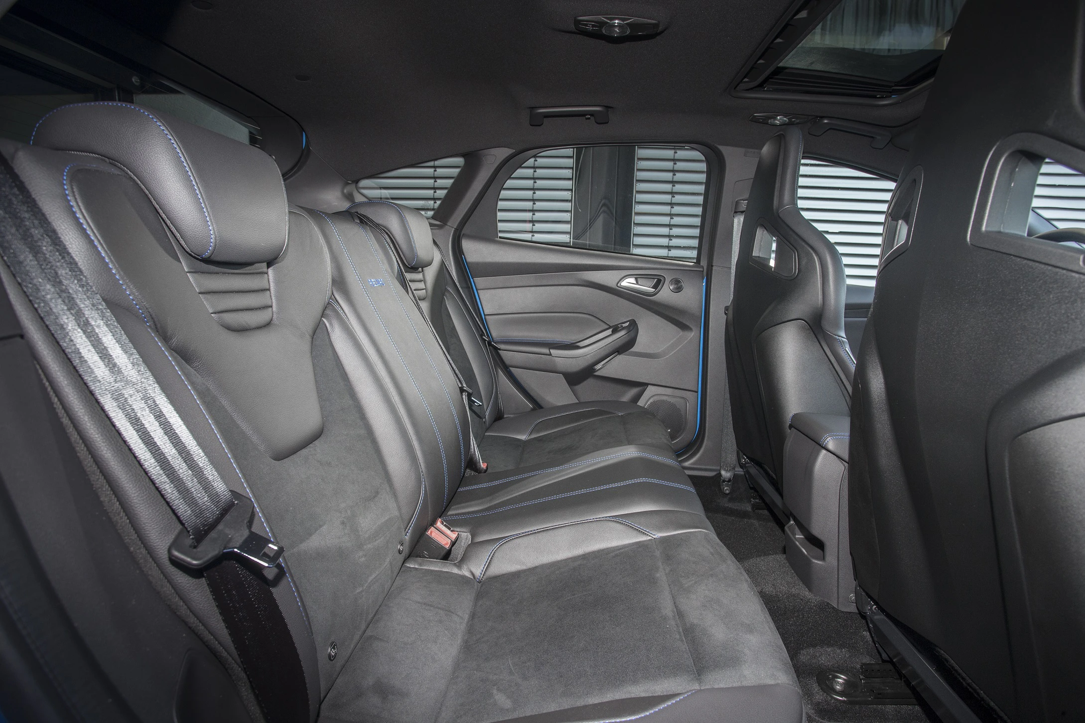 Rückansicht eines Autos mit grauen Ledersitzen und blauen Nähten; sportliches Design mit großzügigem Innenraum und modernen Details.