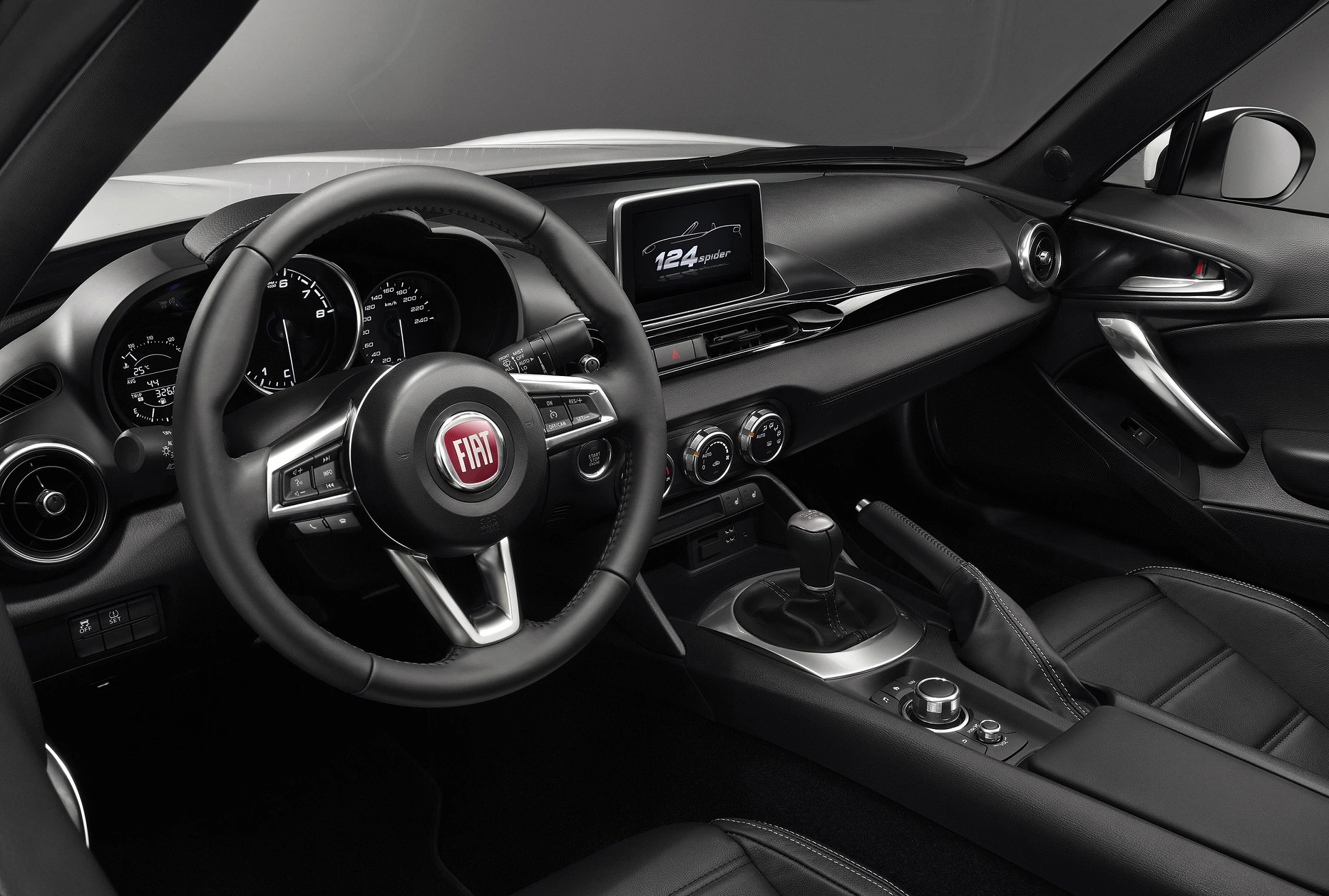 Innenraum eines modernen Fiat-Autos mit Lenkrad, Tachometer und zentralem Bildschirm auf schwarzem Armaturenbrett, Ledersitzen und Schalthebel.