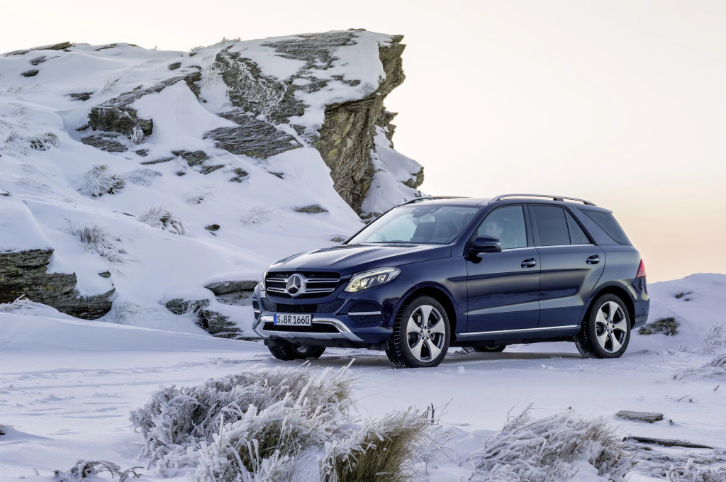 Ein blauer SUV Mercedes-Benz steht auf schneebedecktem, felsigem Gelände bei Sonnenuntergang.