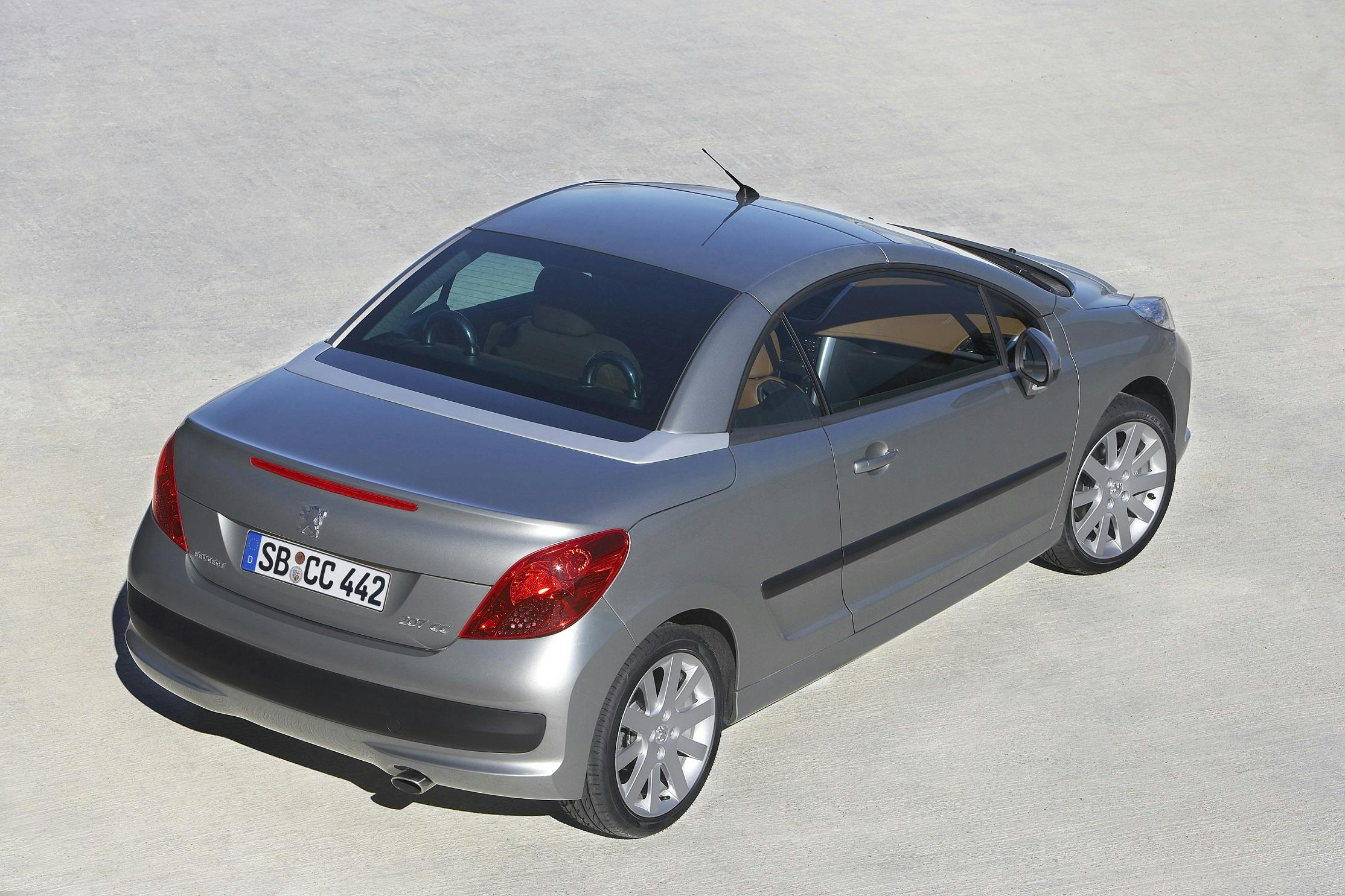 Silbernes Cabriolet-Auto mit geschlossenem Dach, von hinten oben gezeigt, auf hellem Untergrund geparkt.