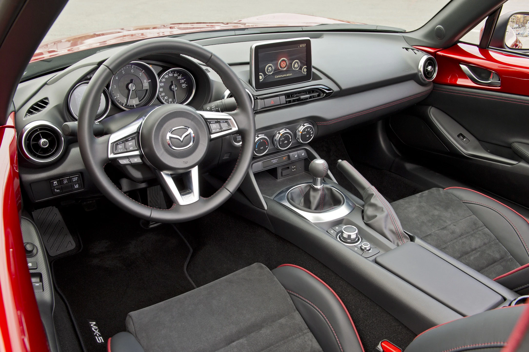 Innenraum eines modernen Autos mit Sportlenkrad, Schalthebel, Armaturenbrett mit Bildschirm und sportlichen schwarzen Sitzen.