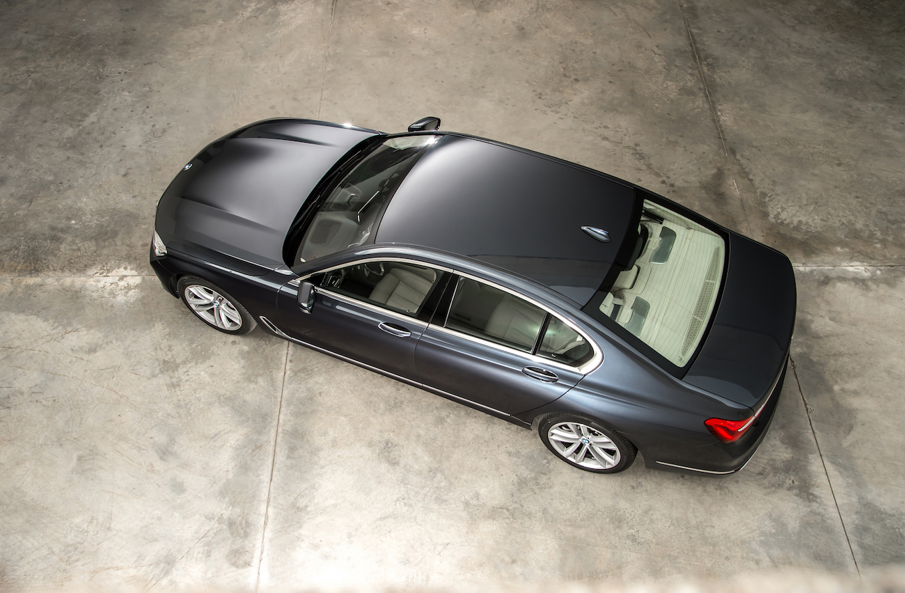 Dunkelgraues Auto in einer Garage aus der Vogelperspektive fotografiert, vorwärts zur linken Seite gerichtet, auf glänzendem Betonboden.