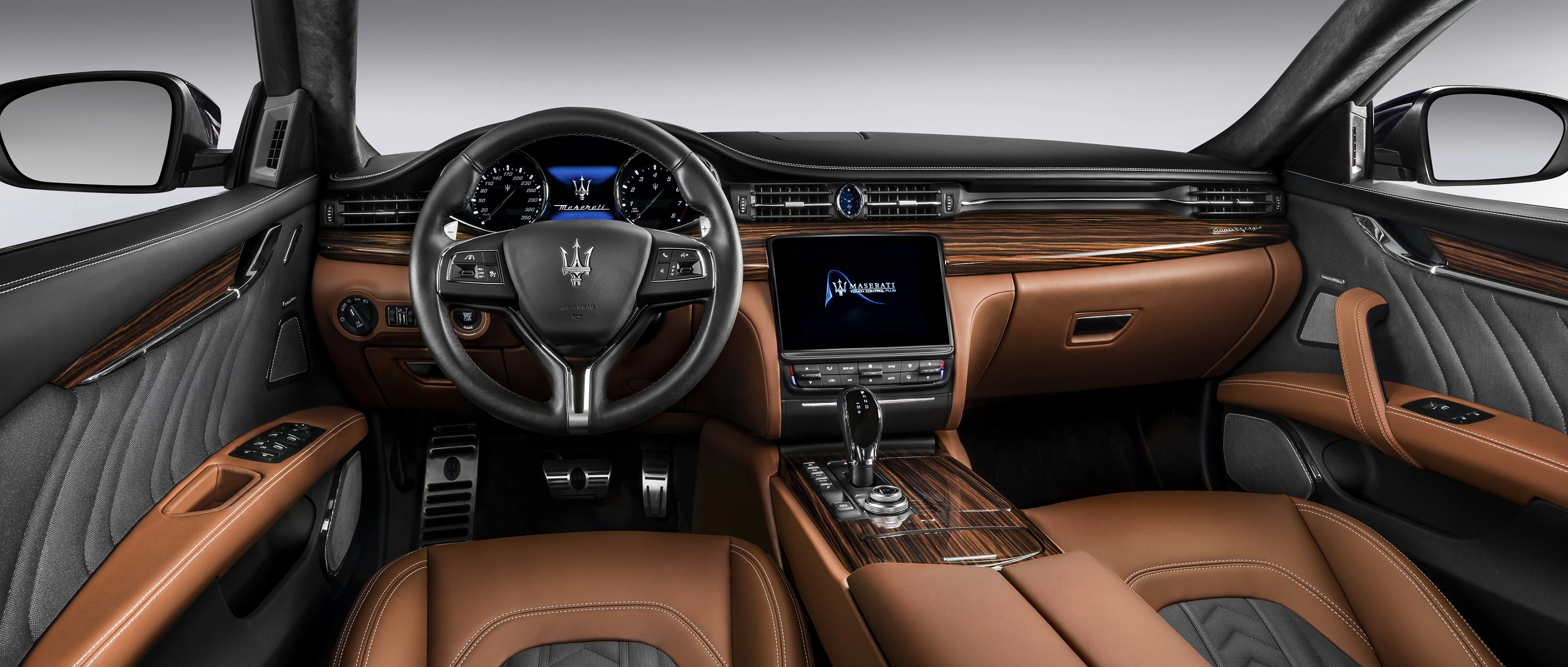 Innenraum eines luxuriösen Autos mit braunen Ledersitzen, modernem Touchscreen-Display, hölzernen Akzenten und einem sportlichen Lenkrad.