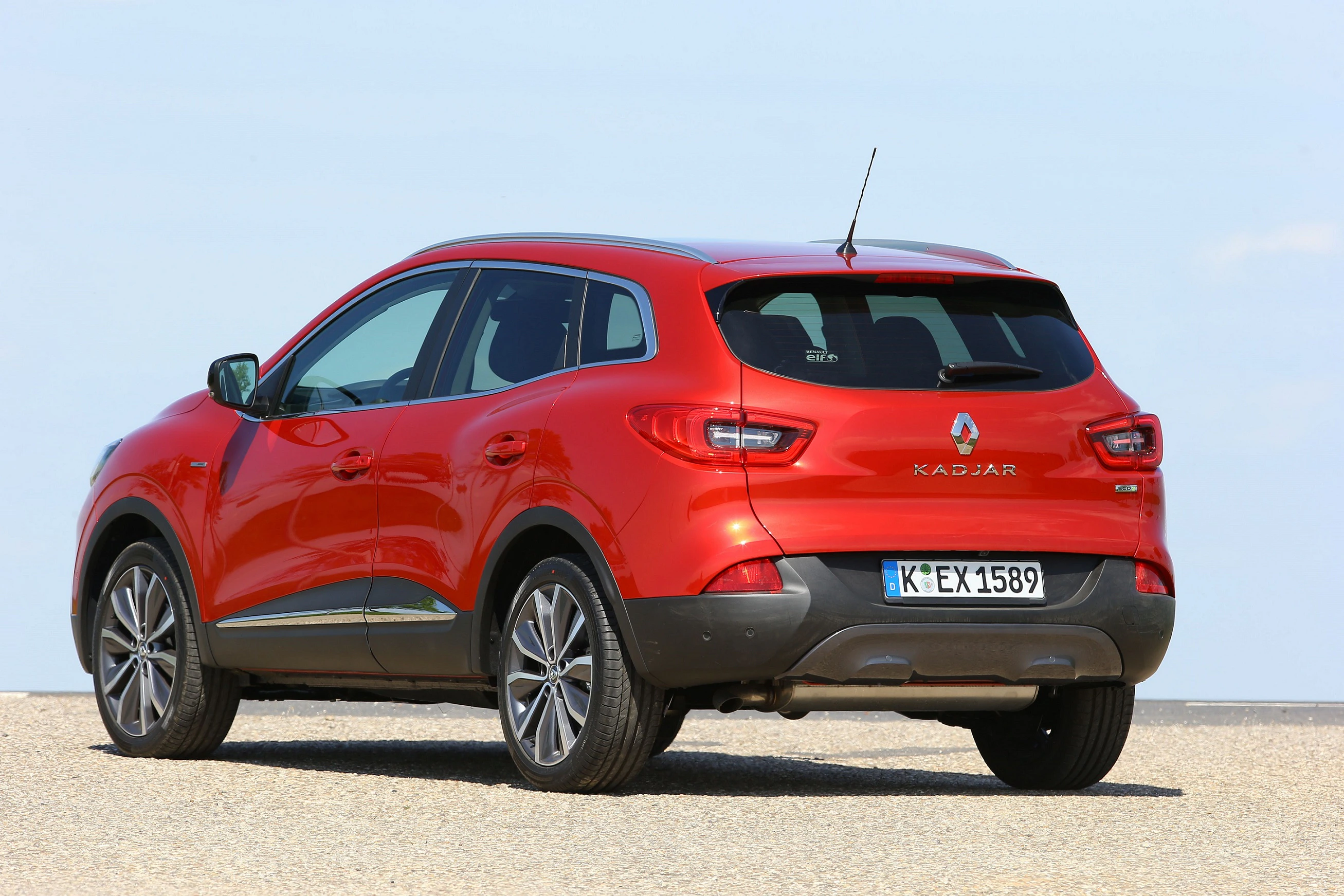 Roter Renault Kadjar SUV steht auf einer Straße vor blauem Himmel, von hinten fotografiert.