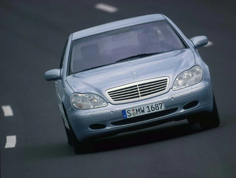 Silberner Mercedes-Benz fährt auf einer Autobahn. Frontalansicht mit sichtbarem Kühlergrill und Scheinwerfern.