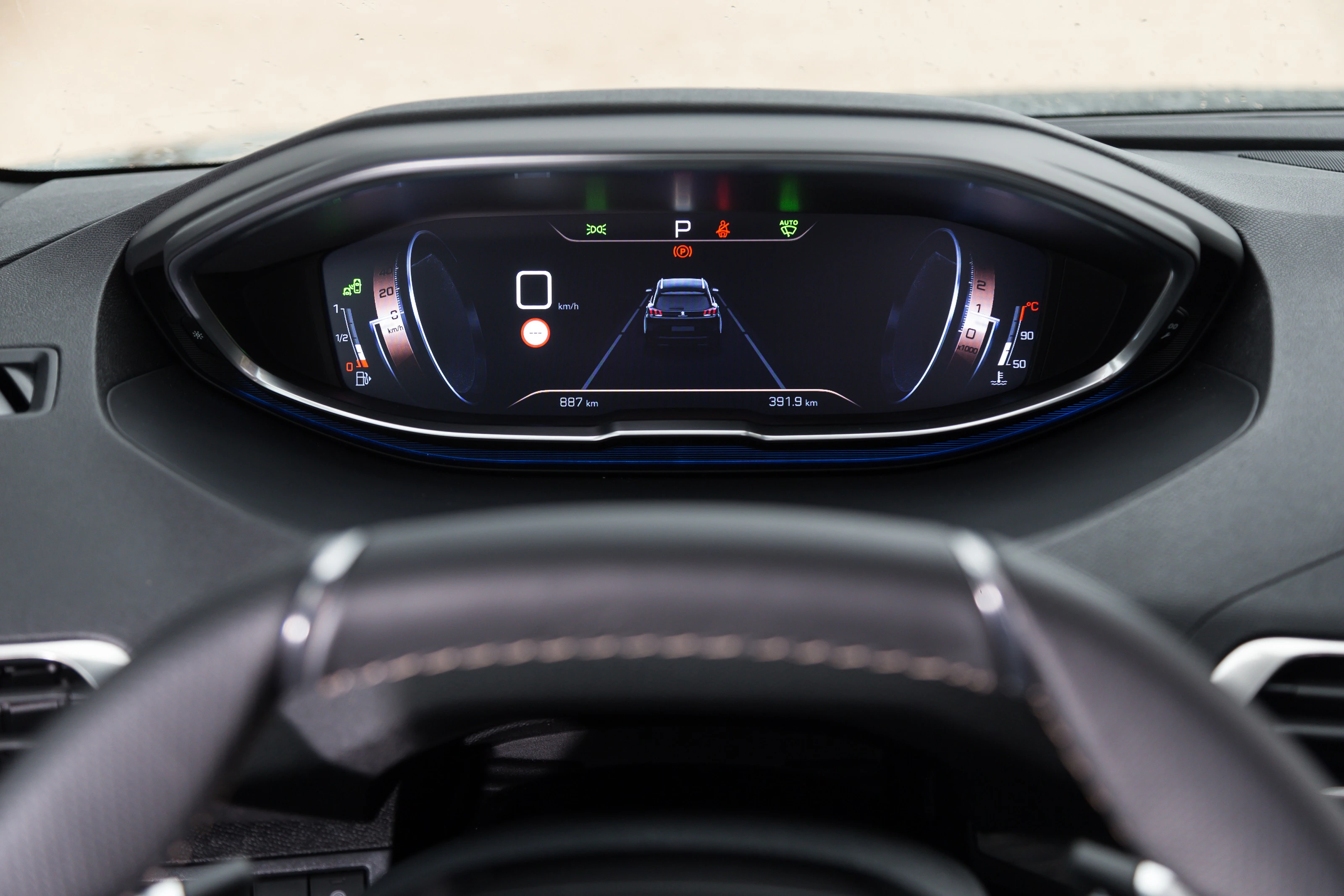 Digitales Armaturenbrett eines Autos mit Geschwindigkeitsanzeige, Fahrspuranzeige und weiteren Symbolen hinter dem Lenkrad.