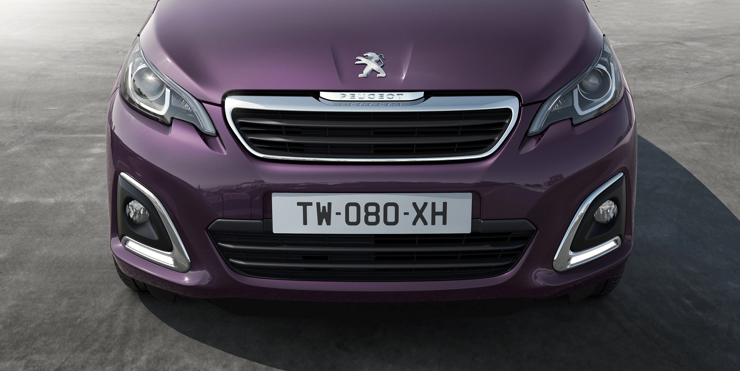 Lila Peugeot 108 von vorne auf grauem Asphalt, Kennzeichen TW-080-XH, mit markantem Kühlergrill und silbernem Logo.