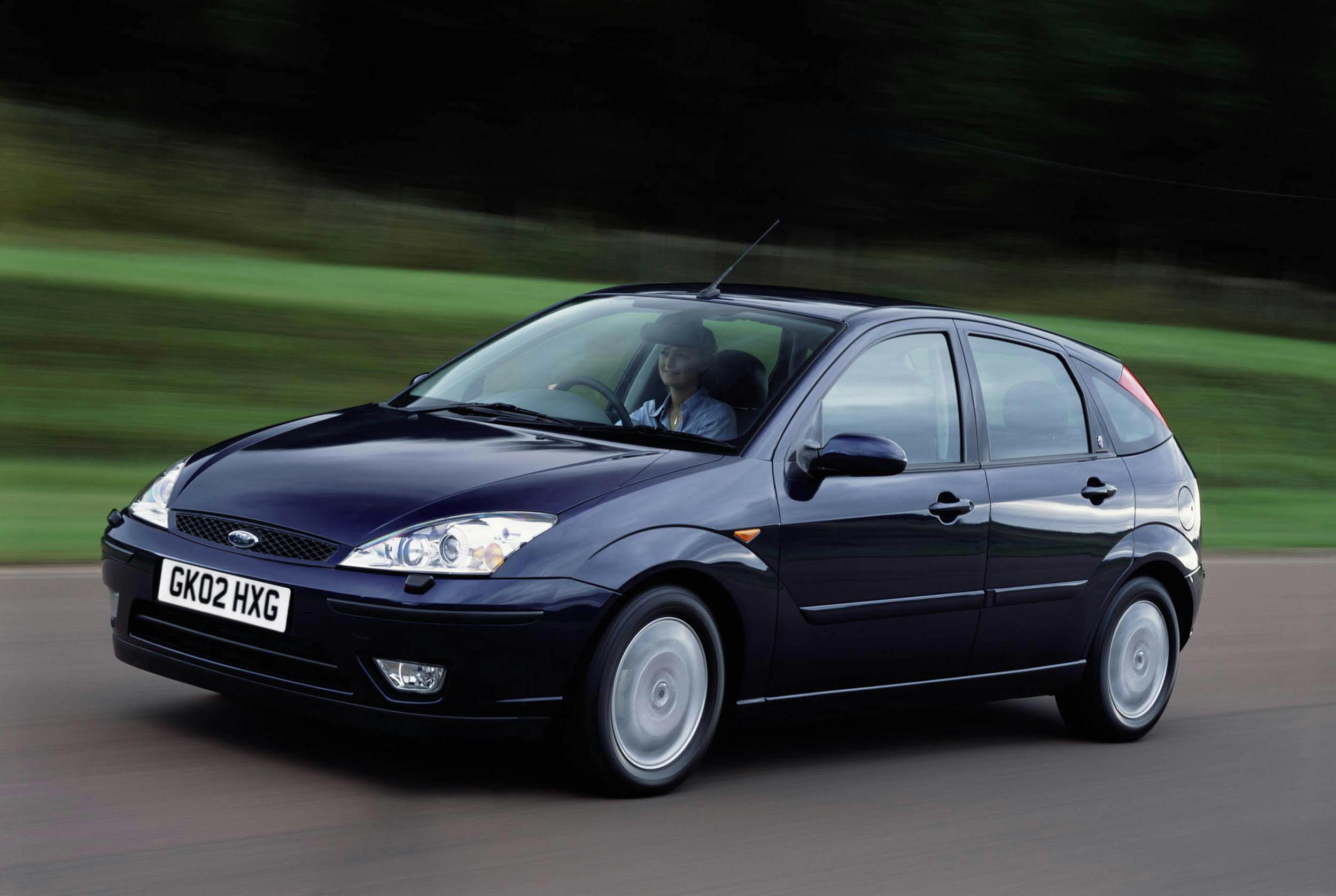 Schwarzer Ford Focus fährt auf einer Landstraße, vorne Design-Elemente sichtbar, grüner Hintergrund.