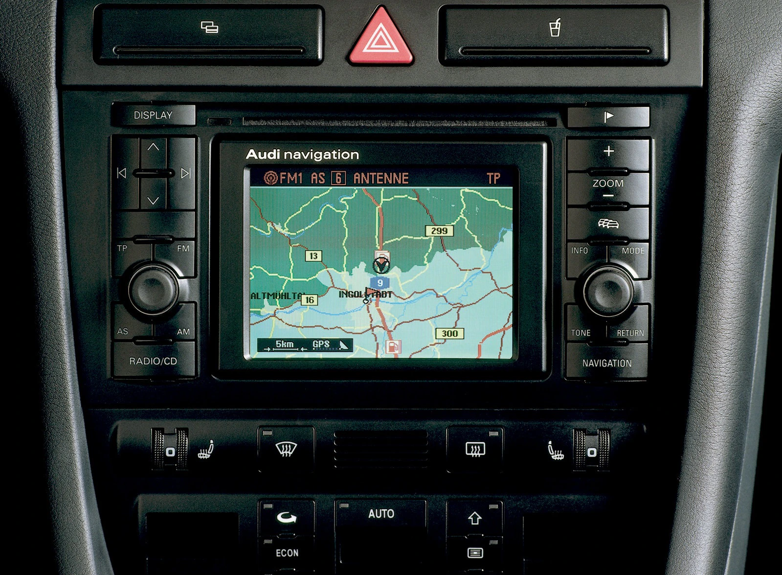 In der Mittelkonsole eines Autos ist ein Navigationssystem zu sehen, auf dem eine Straßenkarte mit Fahrtroute angezeigt wird.