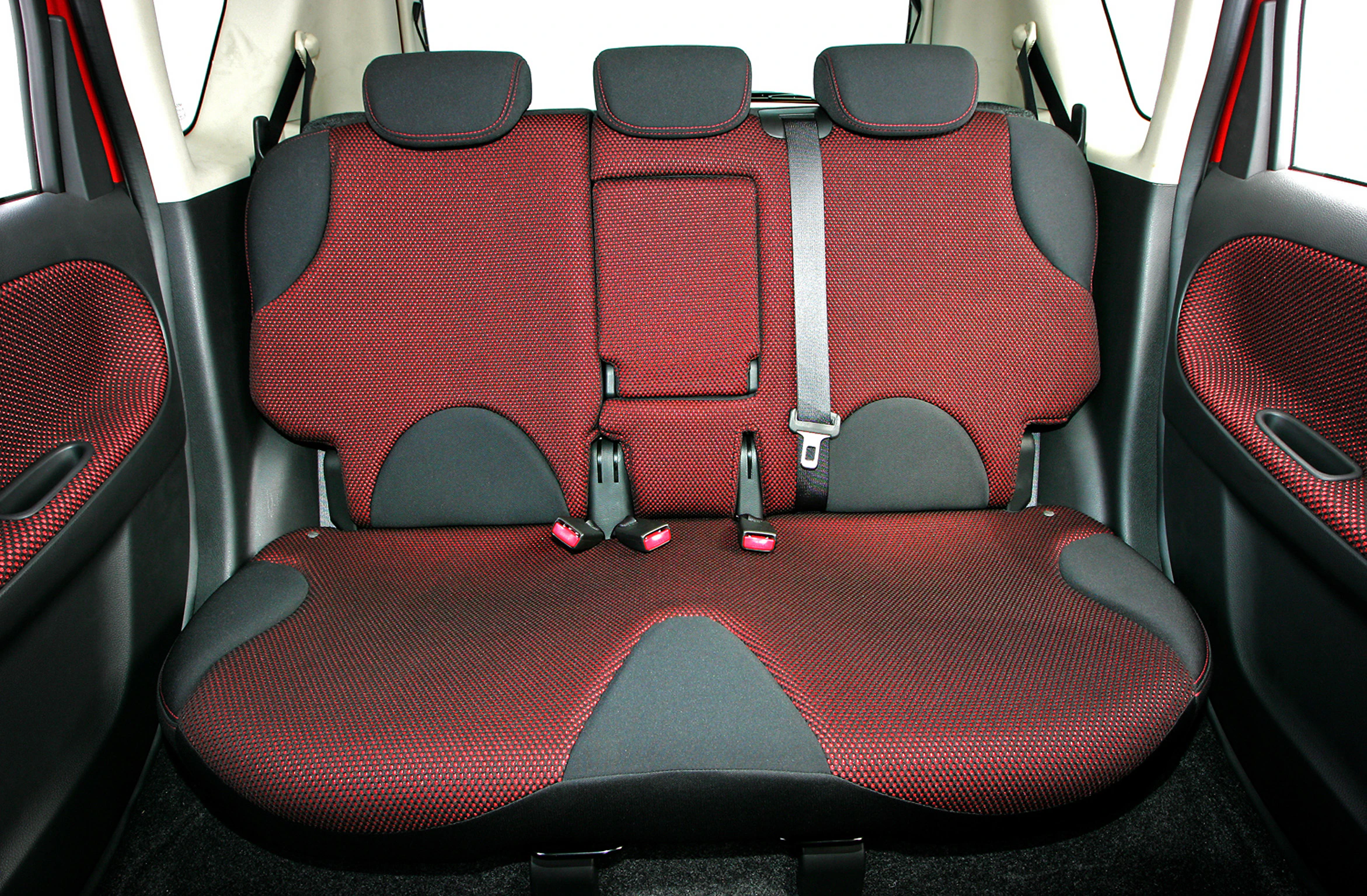 Rückbank eines Autos mit roten und schwarzen Sitzen, zwei Kopfstützen, Sicherheitsgurt und Kindersitzhalterungen.