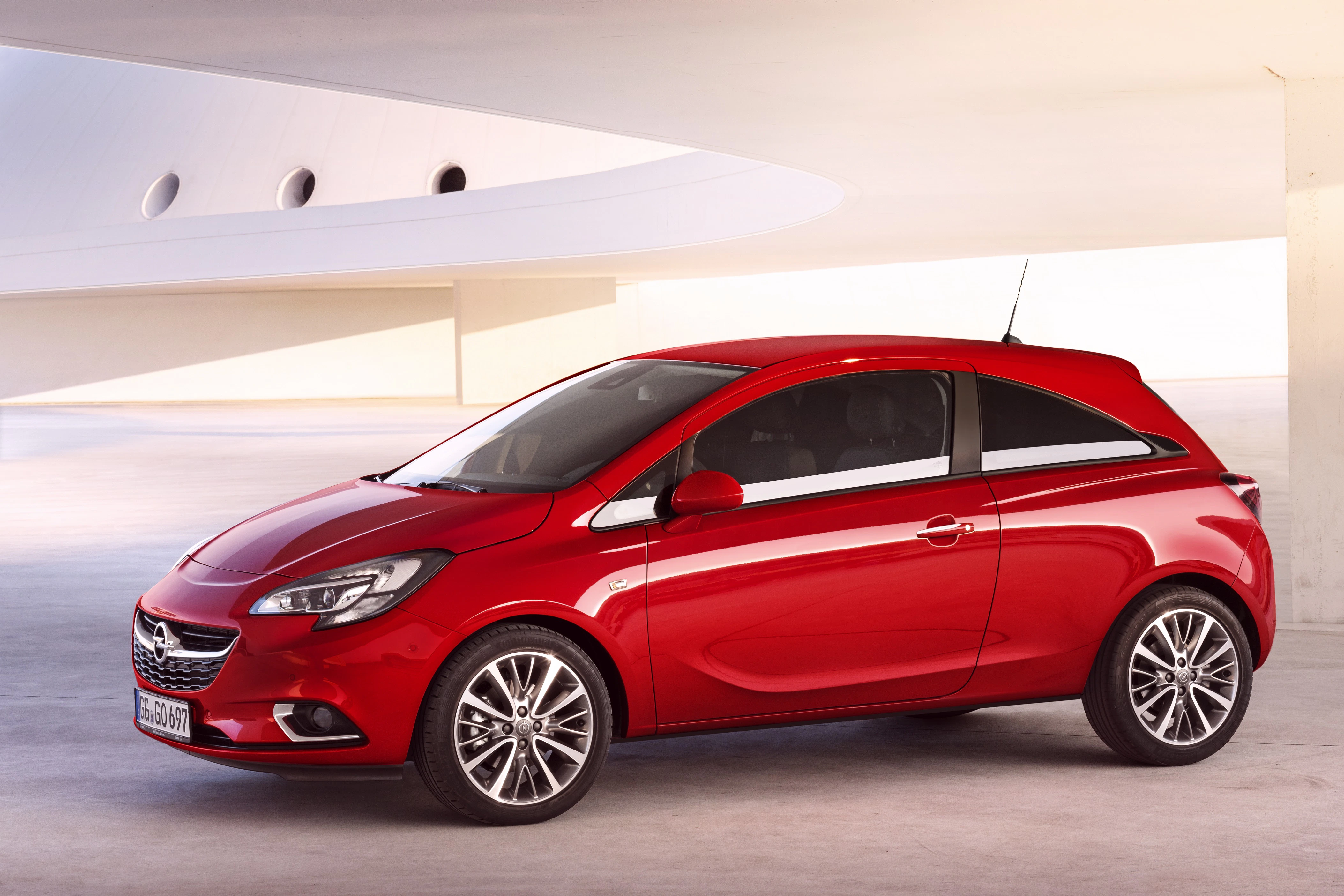 Roter Opel Corsa in moderner Umgebung, seitlich fotografiert. Kompakter Stadtwagen mit dynamischem Design und stilvollen Felgen.