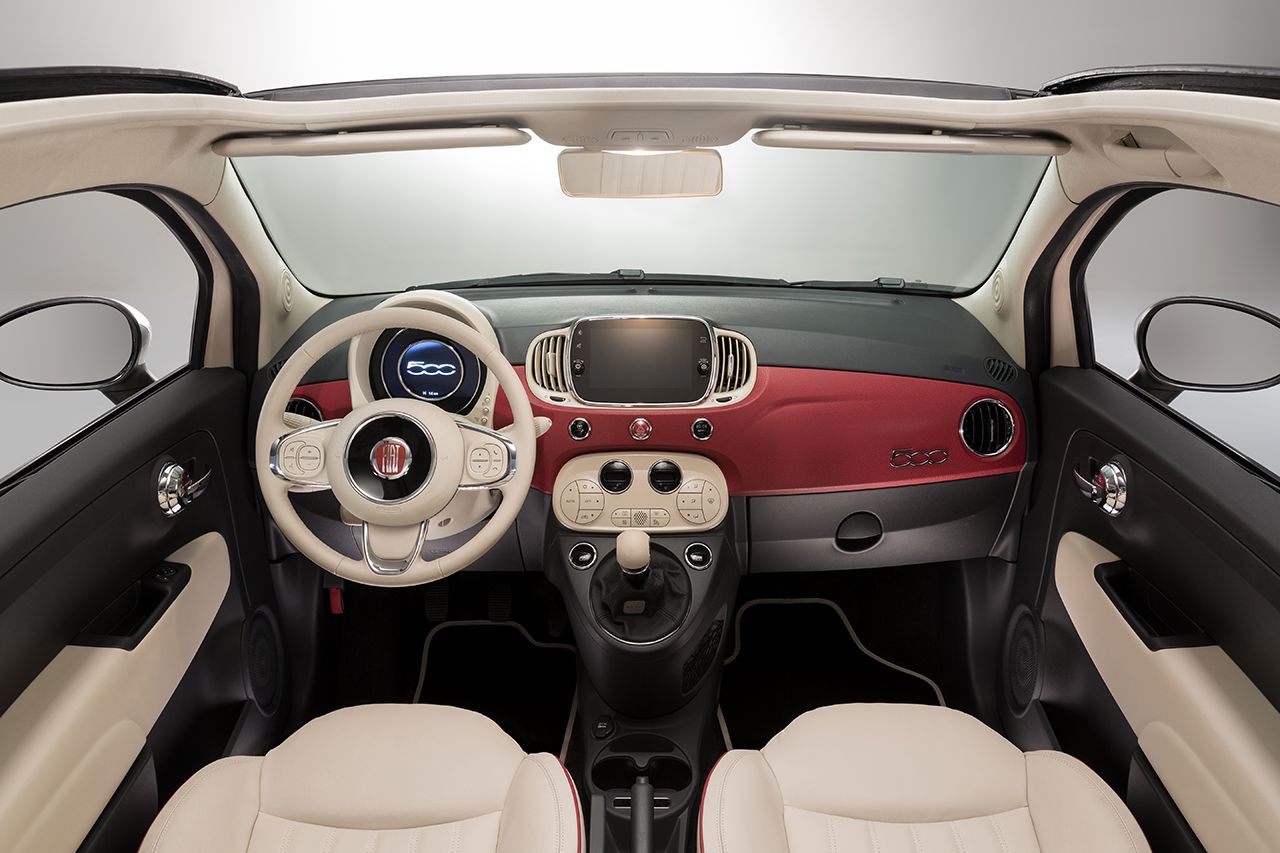 Innenraum eines Fiat 500 mit beigem und rotem Armaturenbrett, Rundinstrumenten, Touchscreen in der Mitte und beigen Ledersitzen.
