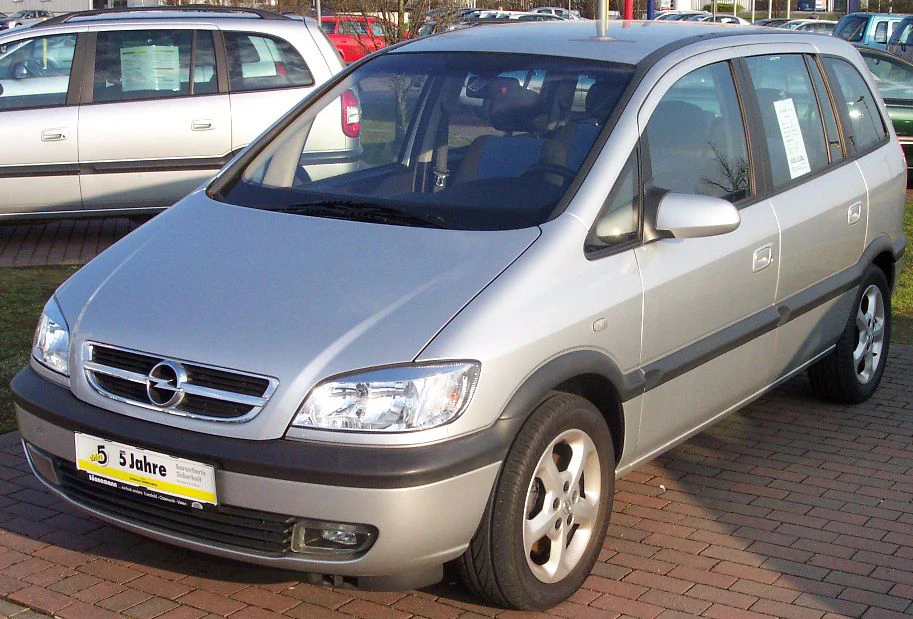 Silberner Opel Zafira-Minivan steht auf einem Parkplatz. Im Hintergrund sind weitere Autos zu sehen.