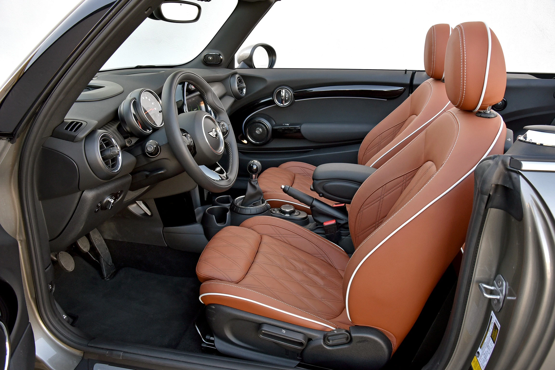 Innenraum eines Autos mit braunem Lederinterieur, einem Lenkrad und einem modernen Armaturenbrett. Sitze sind bequem und elegant gestaltet.