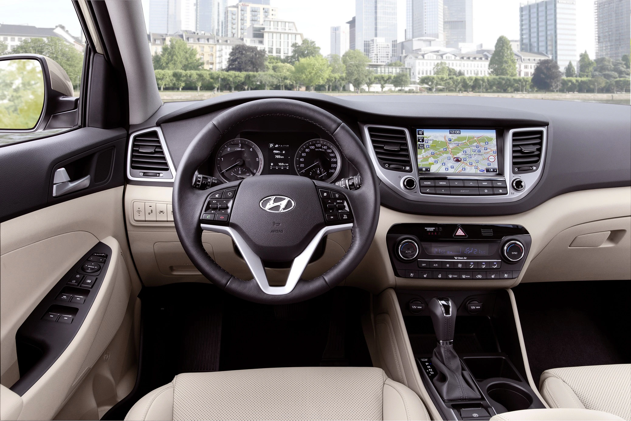 Innenraum eines Autos mit Lenkrad, Armaturenbrett und Navigationssystem. Beige Sitze und städtische Skyline im Hintergrund sichtbar.